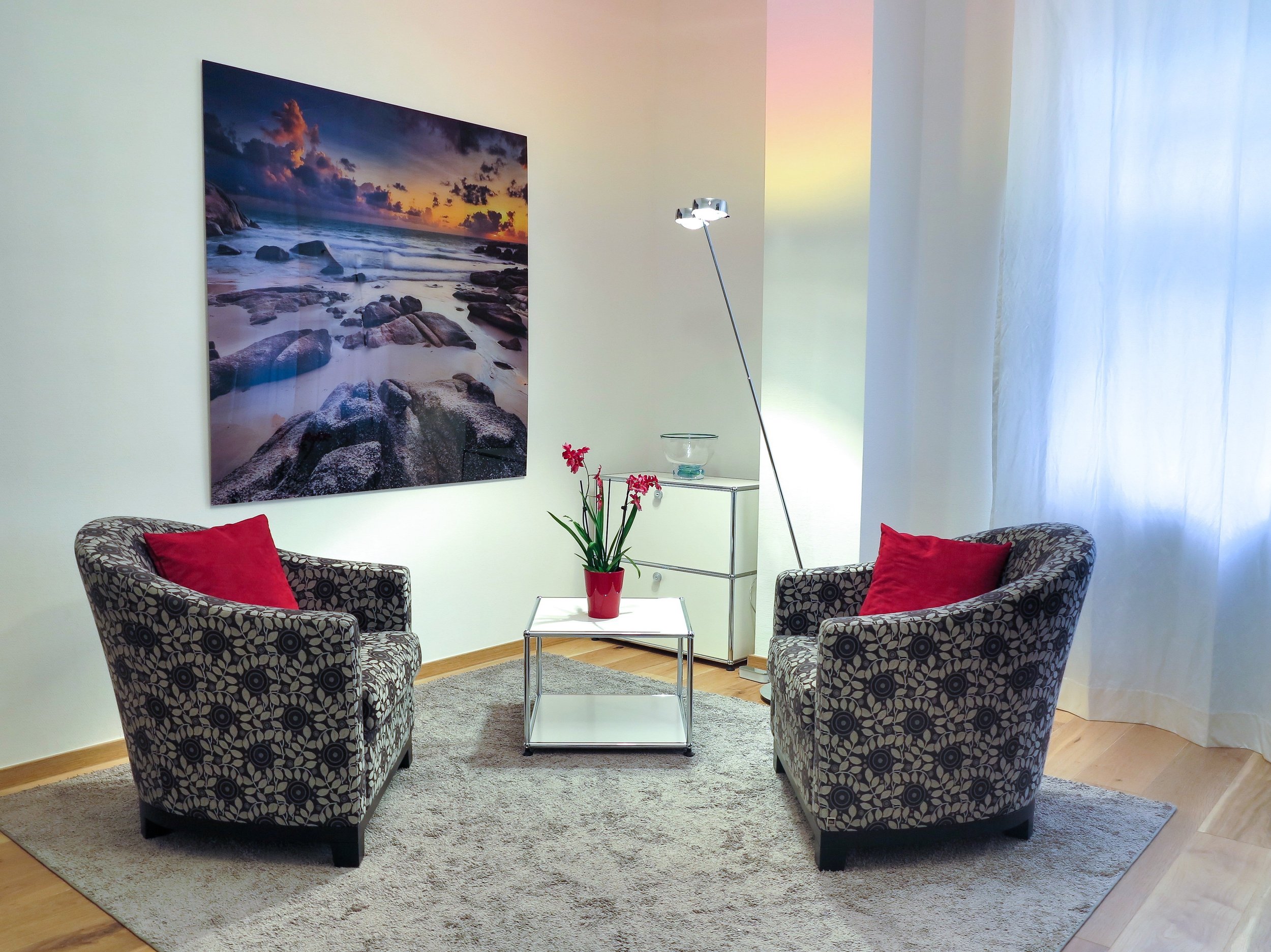 Cozy coaching office with two armchairs, a red flower arrangement, and framed coastal art, where sessions with The Fearless Mind Life Coaching take place.
