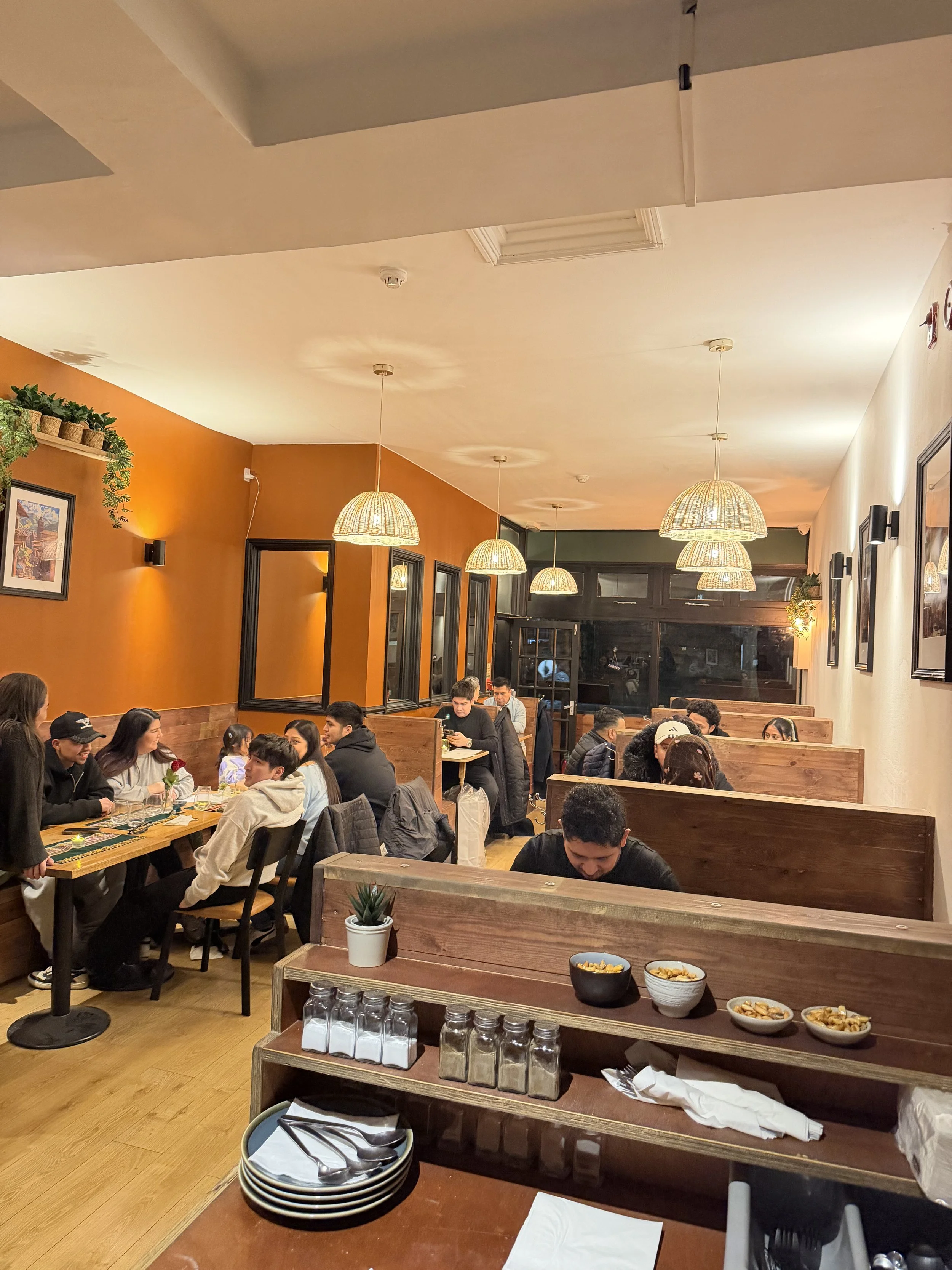 Interior of MAKA Peruvian restaurant in London with diners and wooden seating