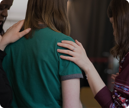 Tres personas en una conversación, con una de ellas tocando el hombro de otra.
