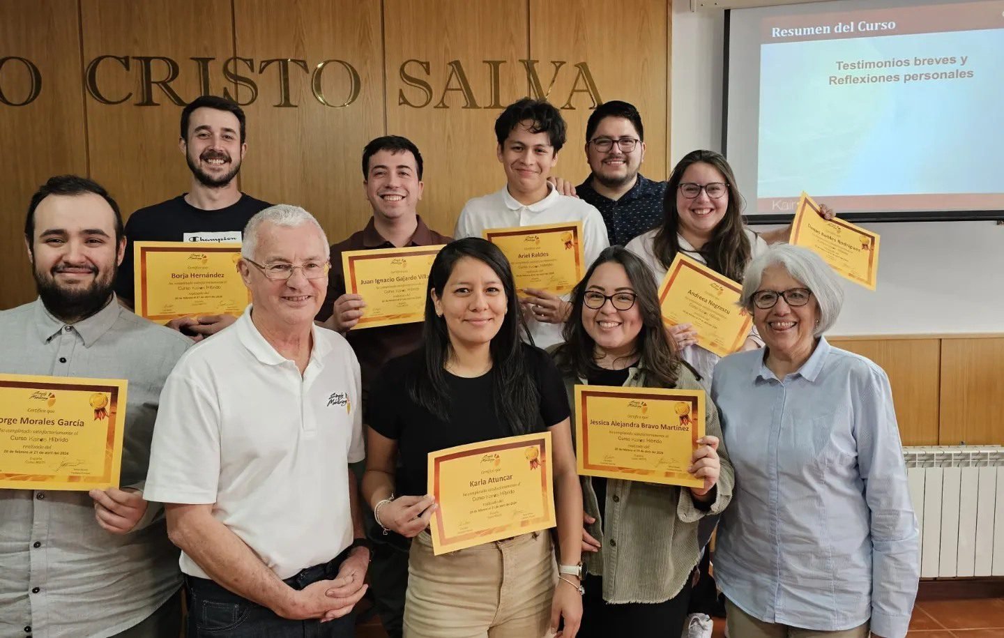 Grupo de personas celebrando, varias sosteniendo certificados, en un entorno académico o de ceremonia