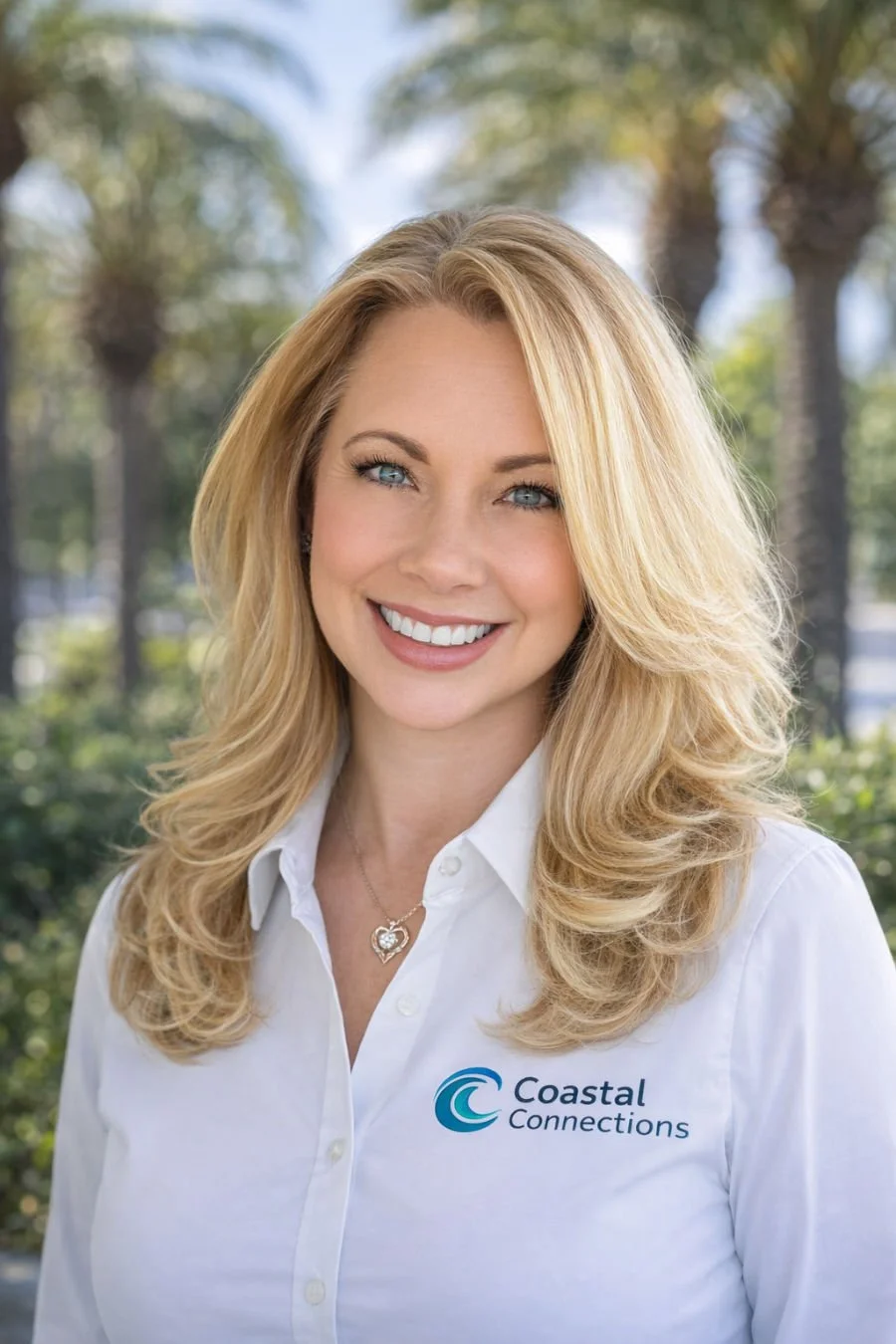 A woman with long blonde hair smiling outdoors, wearing a white company shirt with the Coastal Connections logo.