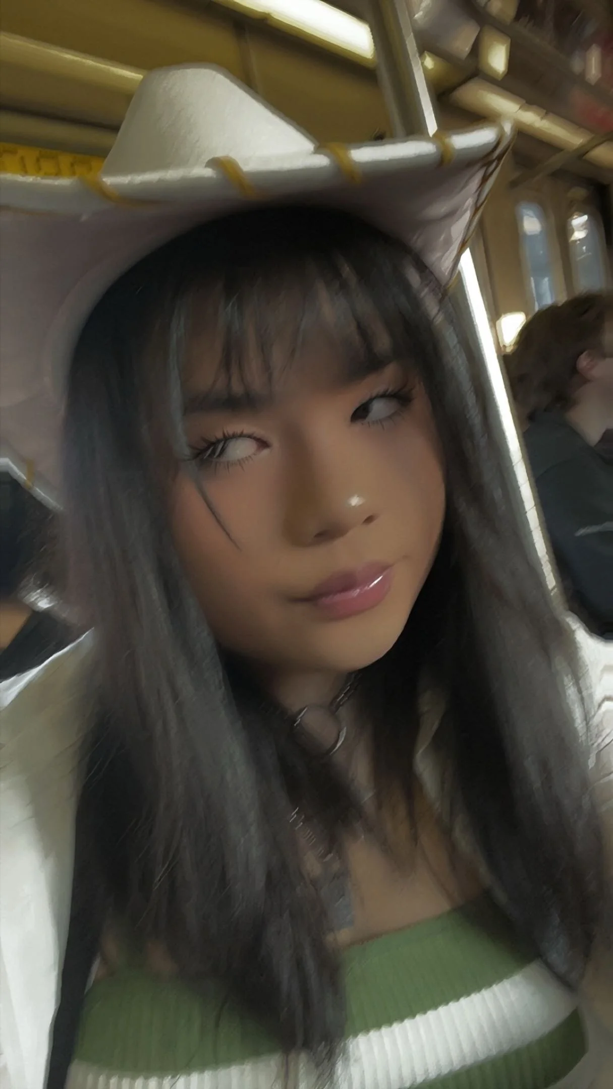 A young woman with long dark hair and bangs, wearing light makeup, a necklace, and a green and white striped top, sitting on a bus with her head resting on her hand, looking to the side with her eyes slightly closed.