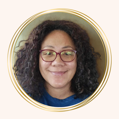 Woman with dark curly hair and red glasses, smiling.