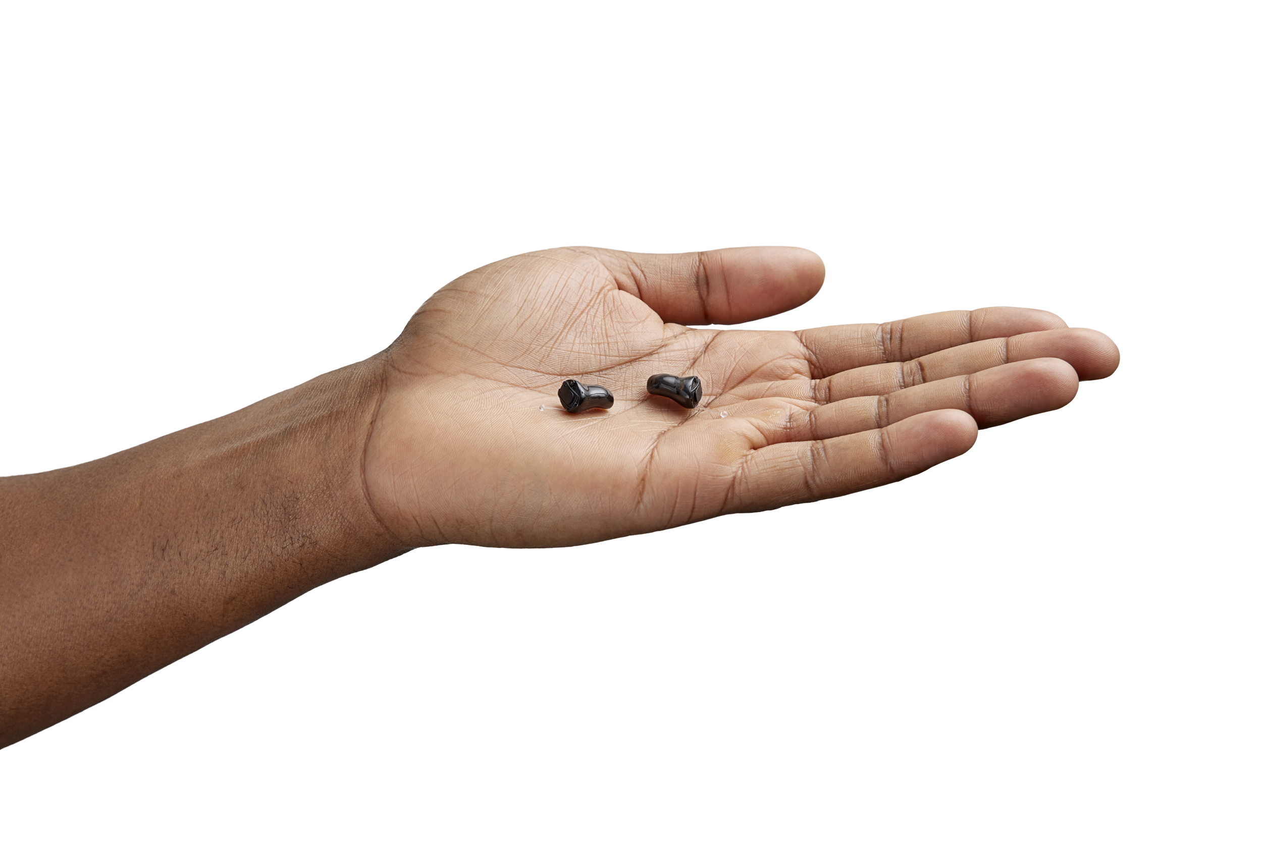 A hand holding two small, black Oticon Zeal hearing aids.