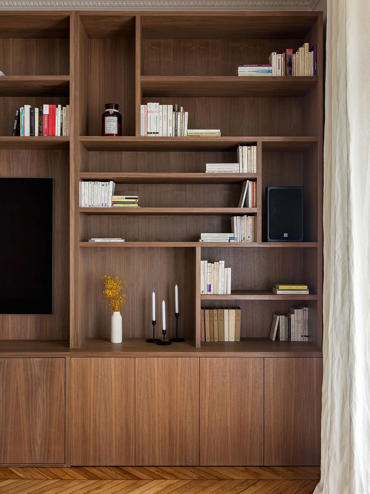 Noa Pariset Architecture d'intérieur - Saint-Michel - Rénovation d'un appartement de 160 m² - Une bibliothèque sur-mesure en bois foncé noyer toute hauteur chaleureuse en conviviale.