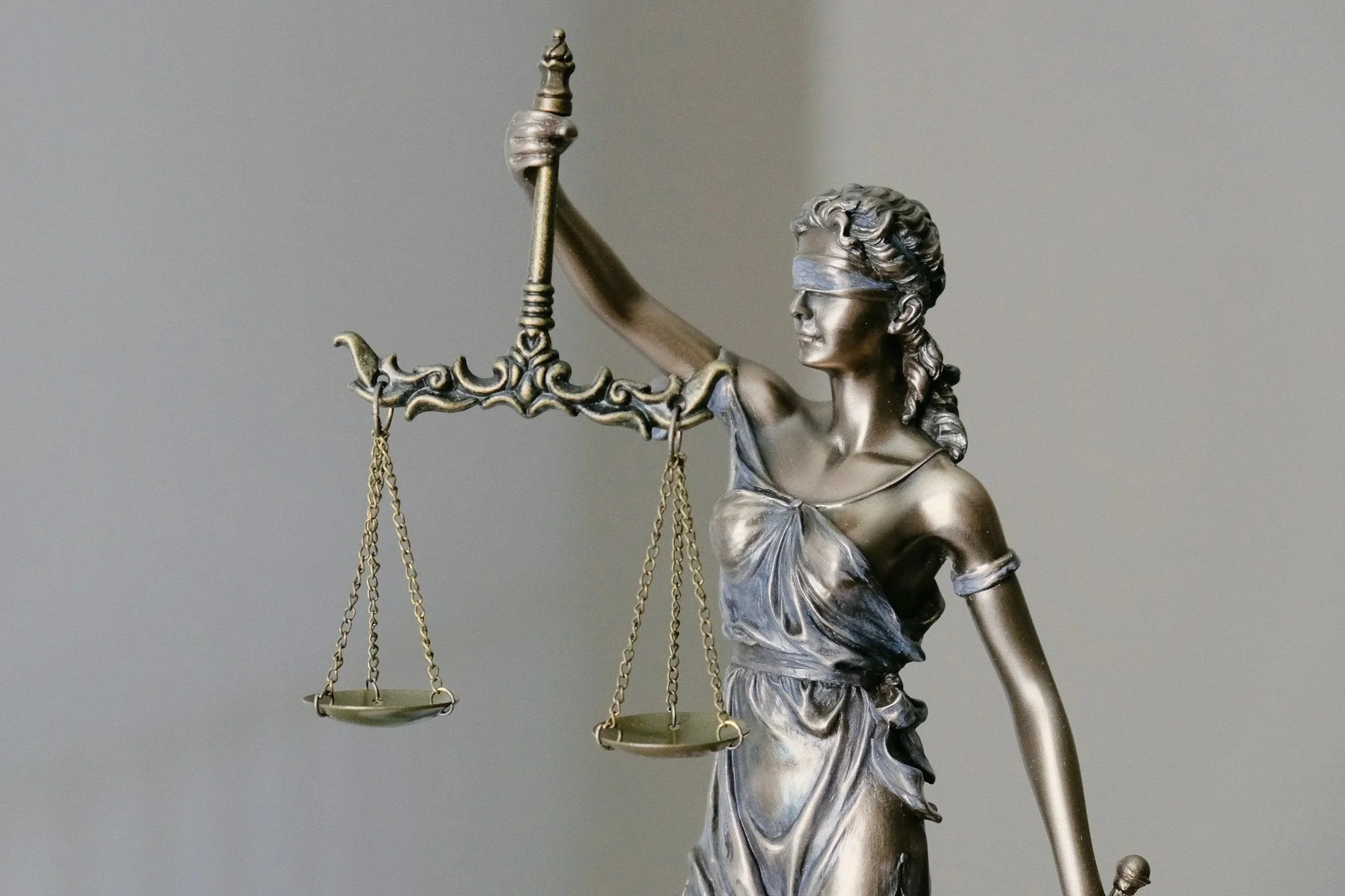 A metallic sculpture of Lady Justice holding scales and a sword.