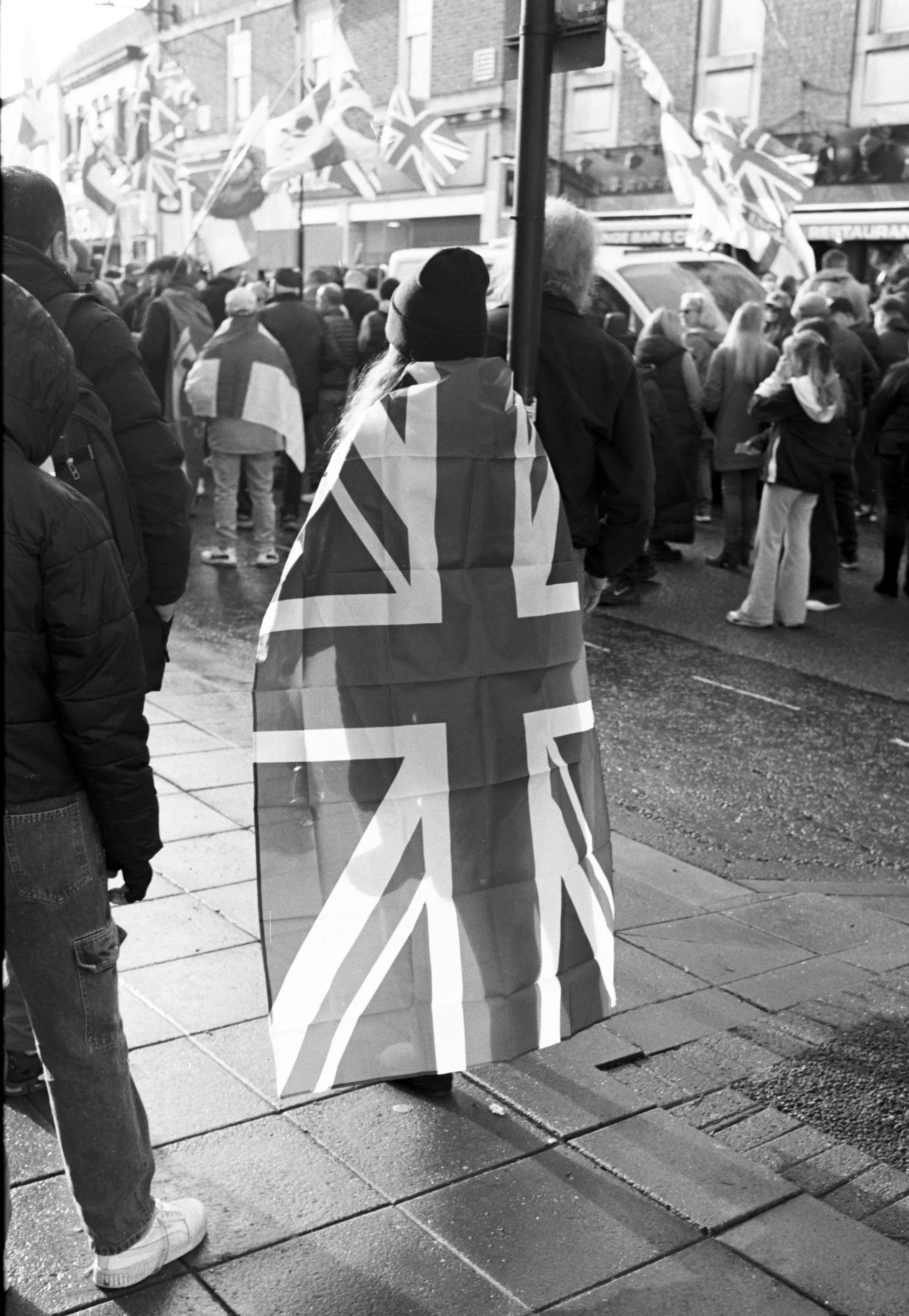 Marcher draped in a Union Jack flag, seen from behind