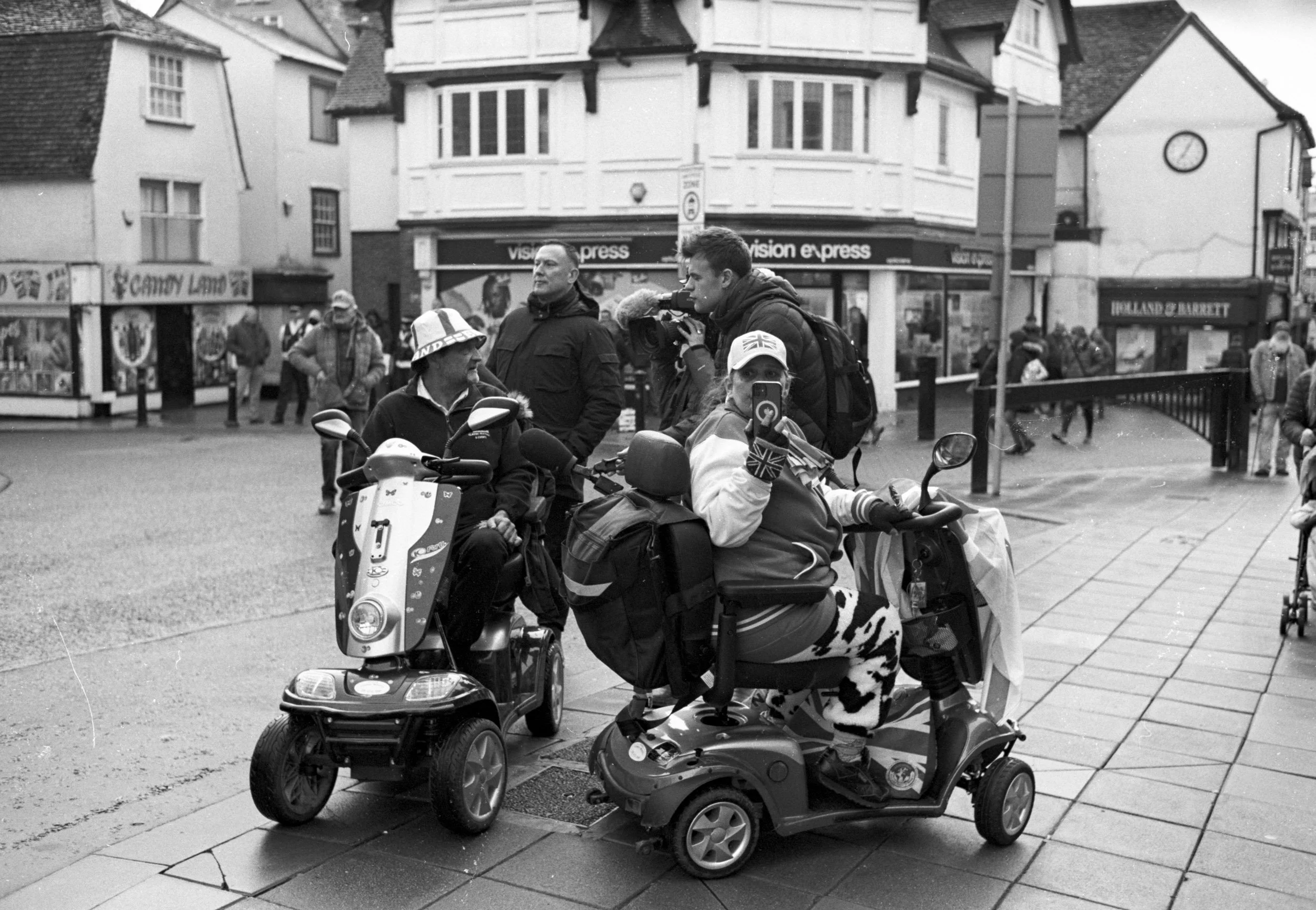 Mobility scooters at the head of a street march, one man filming