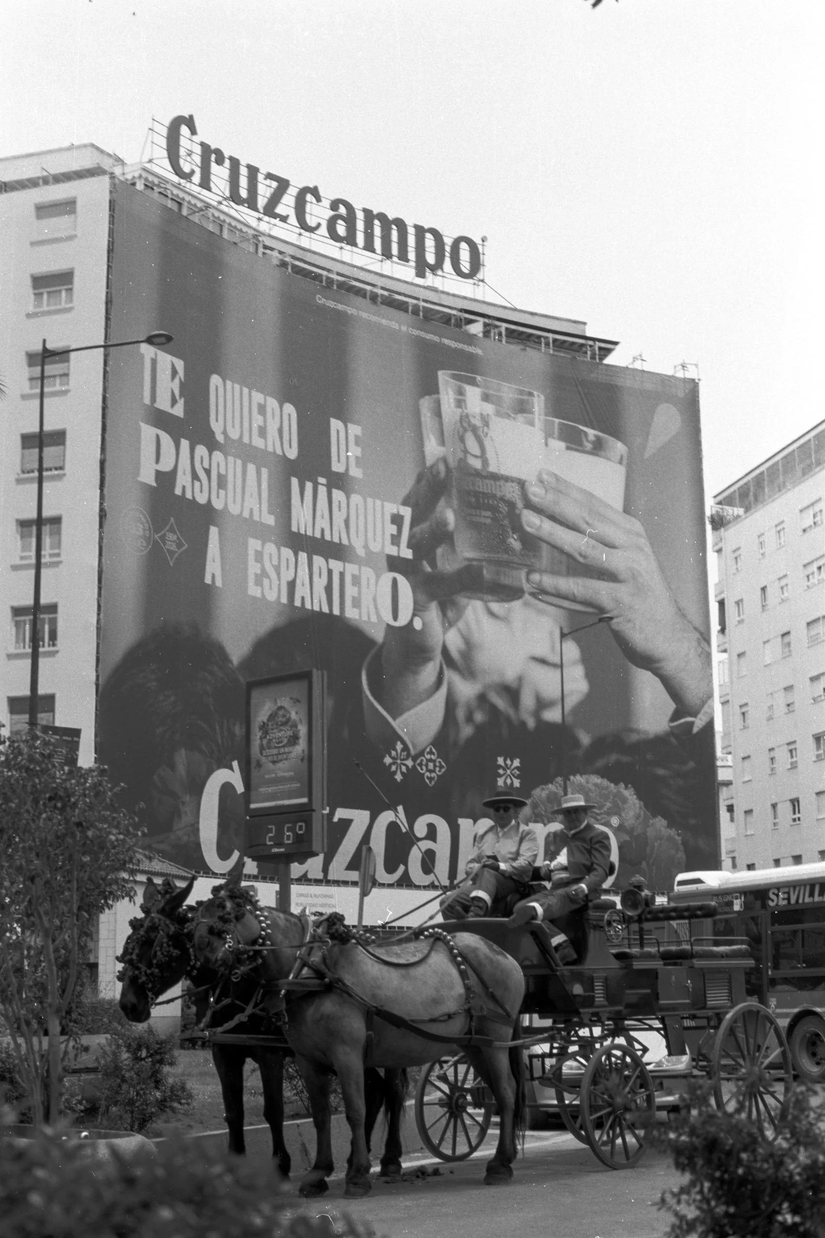 Mule carriage passing beneath a giant Cruzcampo beer billboard, Seville