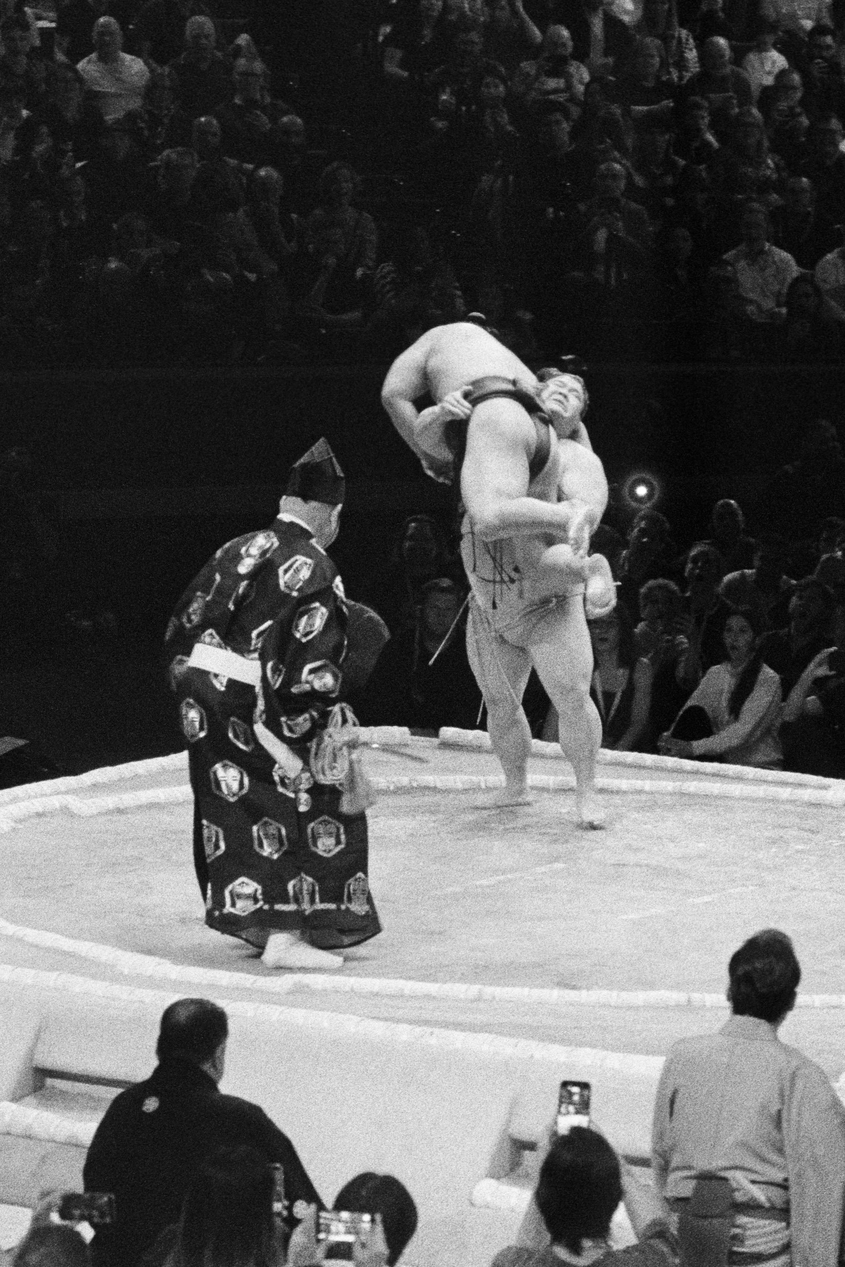 A wrestler carries his opponent bodily out of the ring