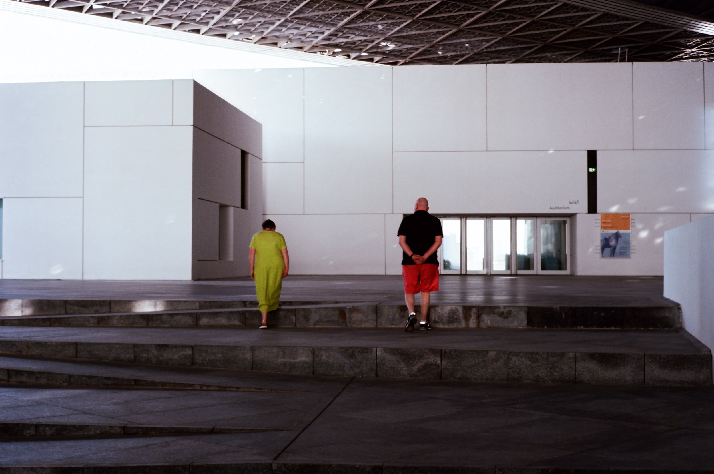 Woman in a lime dress and a contemplating man on the museum steps