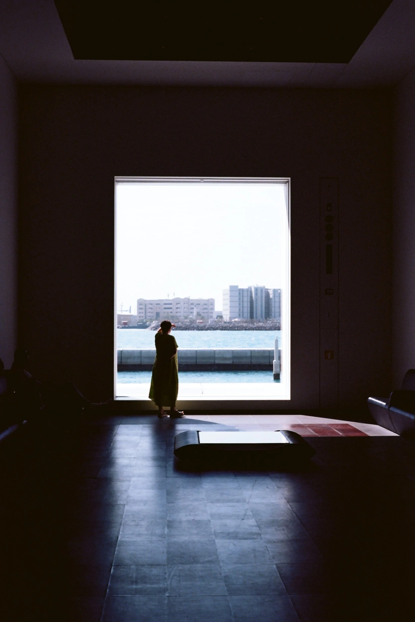 Woman in a green dress at a vast harbour window