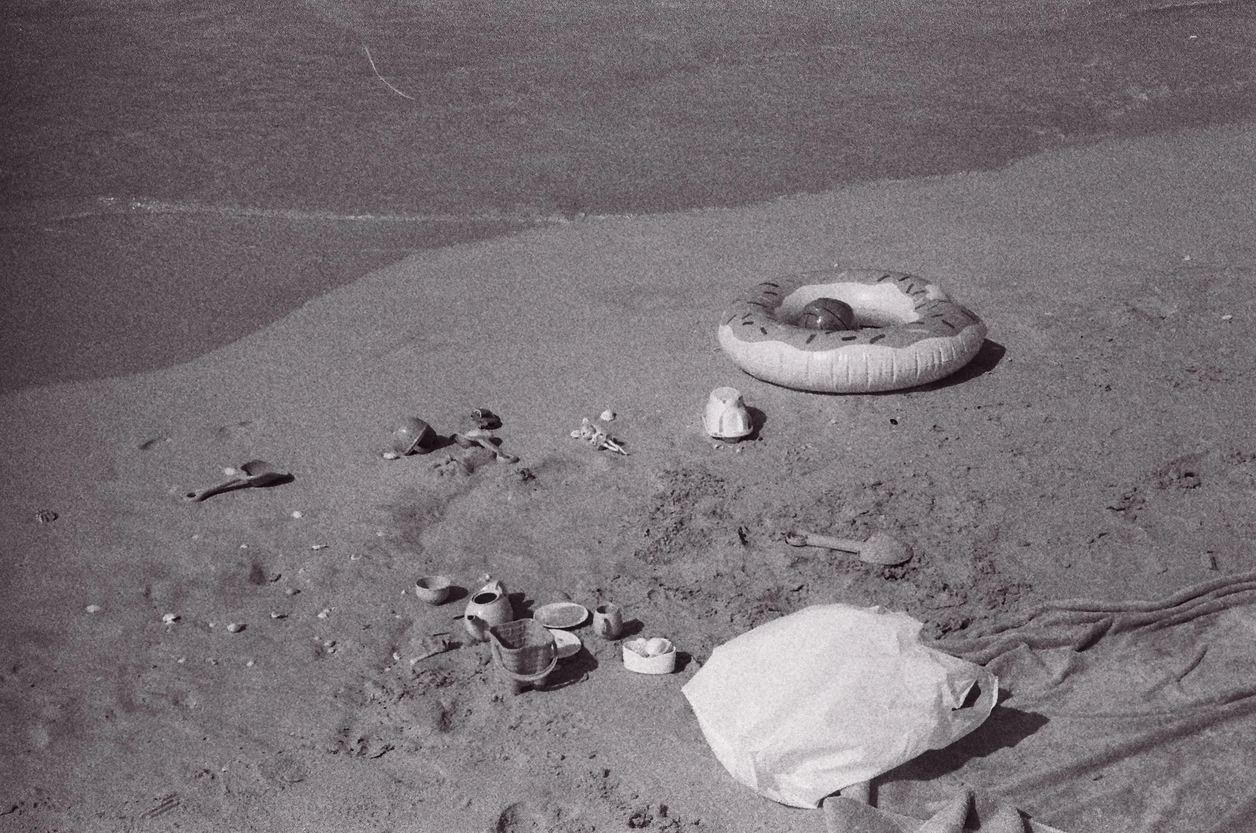 Abandoned children's toys, a tea set and an inflatable ring on the sand