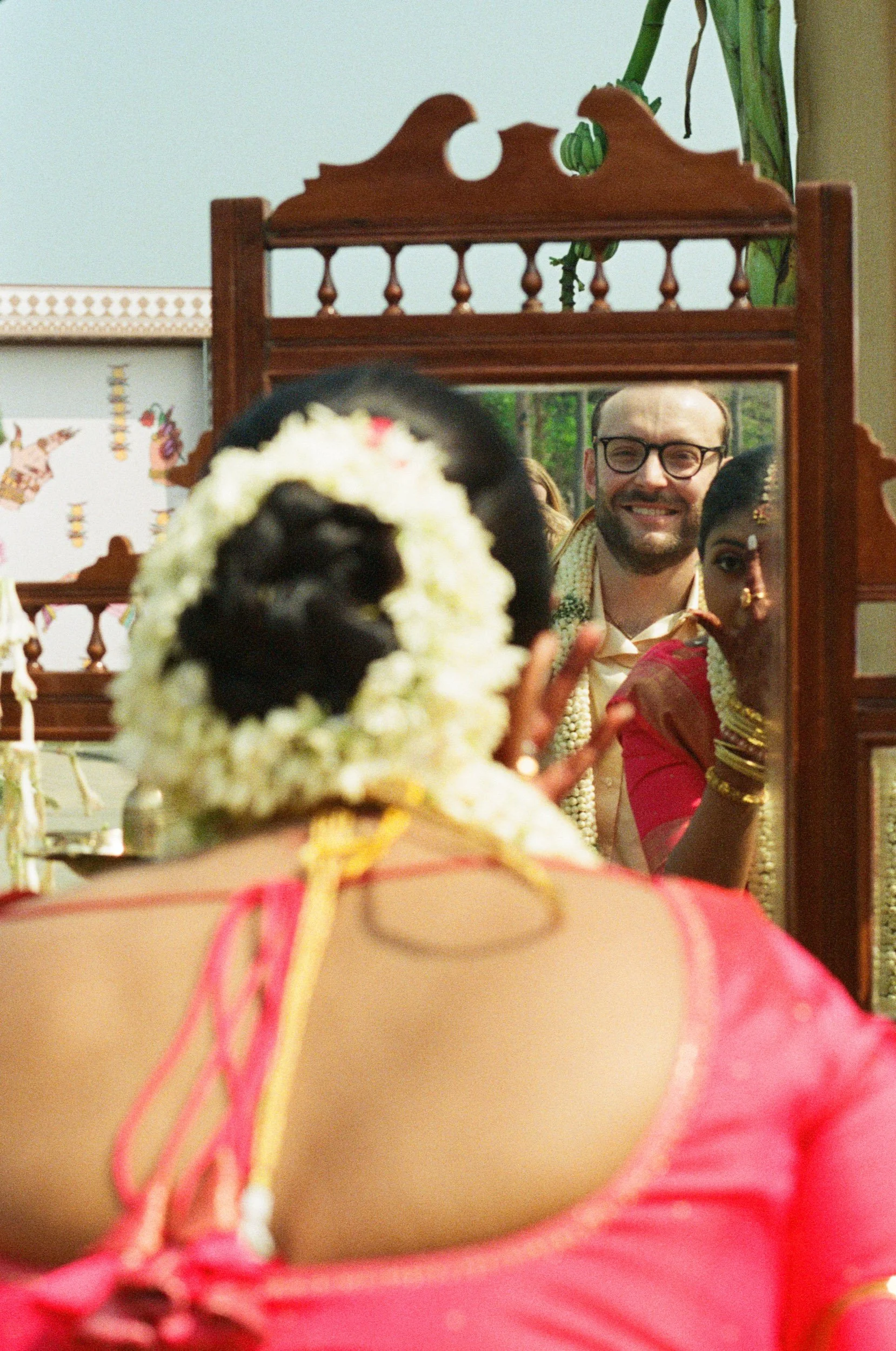 Groom smiling into a carved dressing mirror before an Indian wedding ceremony