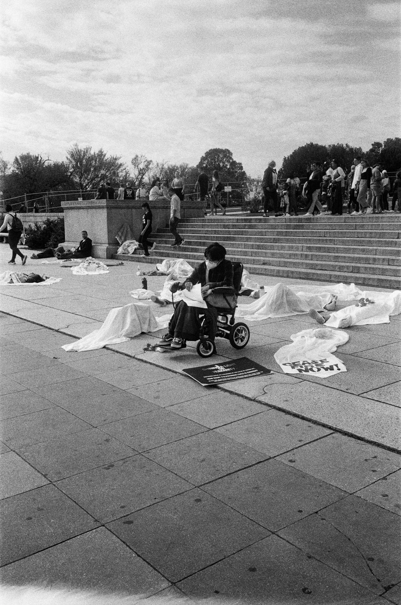 Protester in a wheelchair among shrouded figures at a die-in