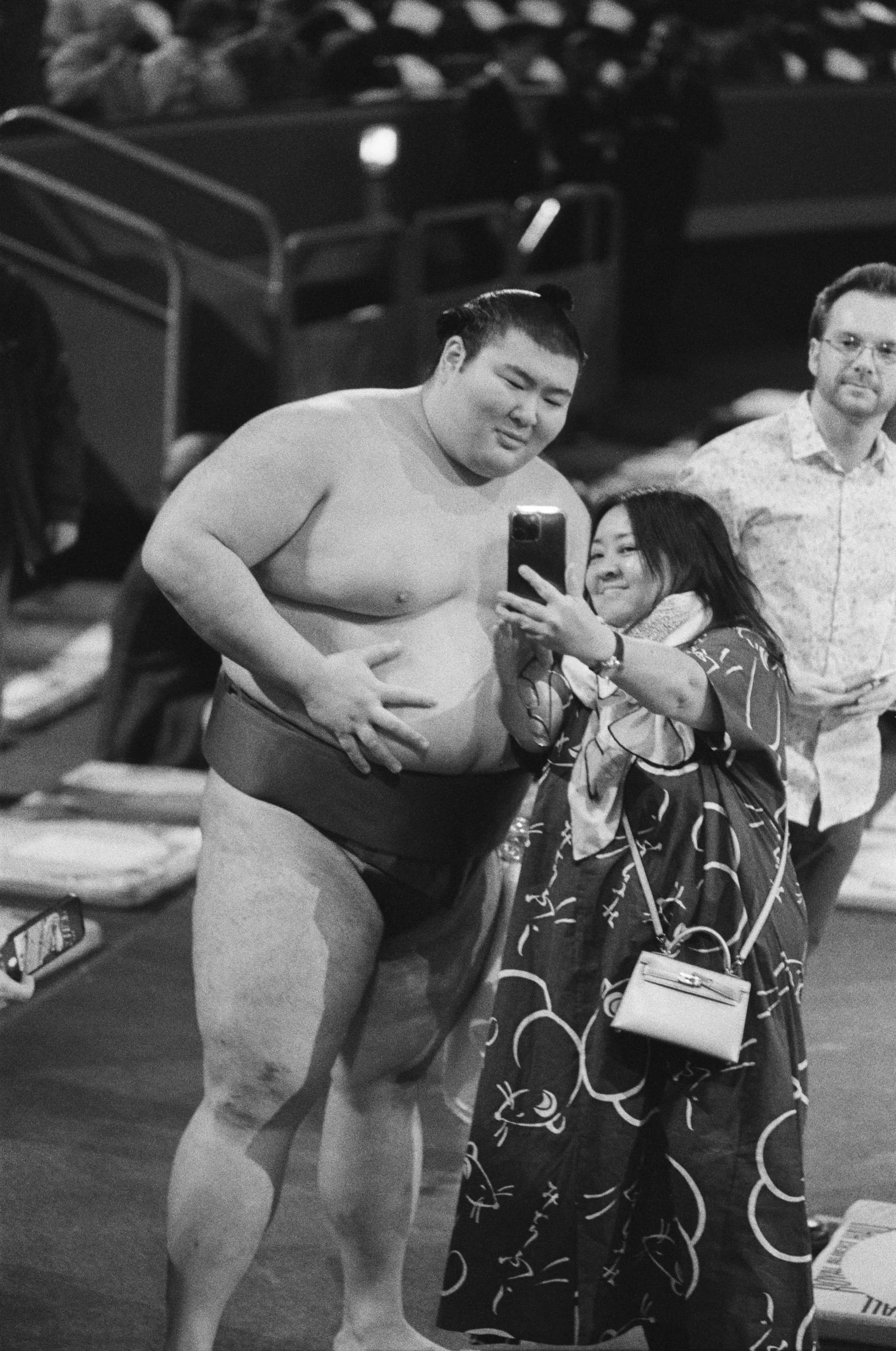 A fan takes a selfie with her hand on a wrestler's belly