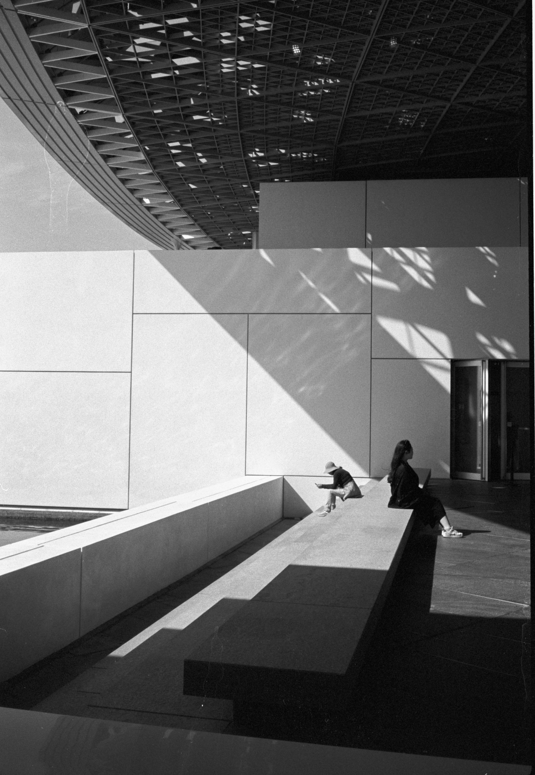Two figures in dappled light beneath the dome of the Louvre Abu Dhabi