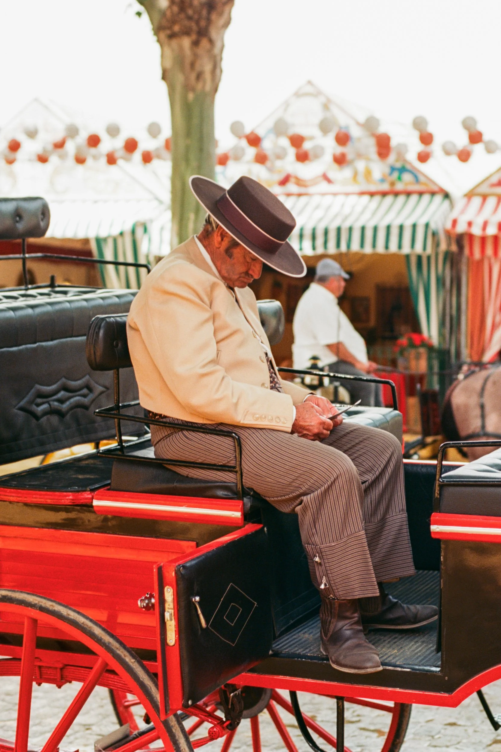 Coachman in a wide-brimmed hat writing on his carriage box at the Feria de Sevilla