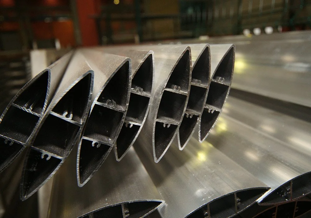 Close-up of steel pipes with internal support structures stacked in a factory setting.