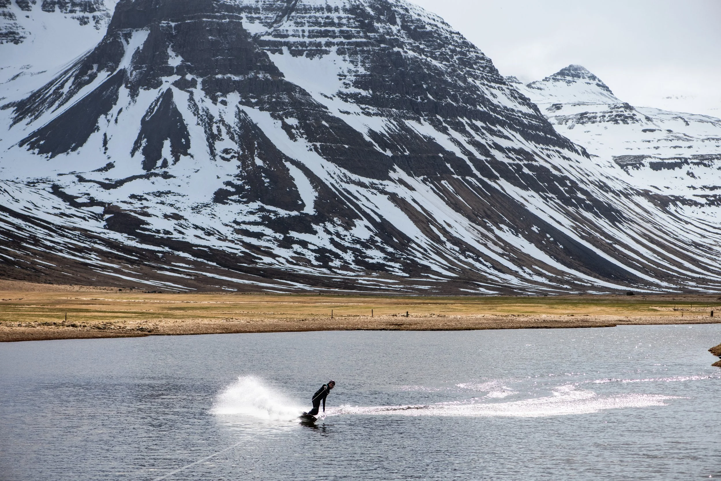 A person water skiing on a lake with snowy mountains in the background