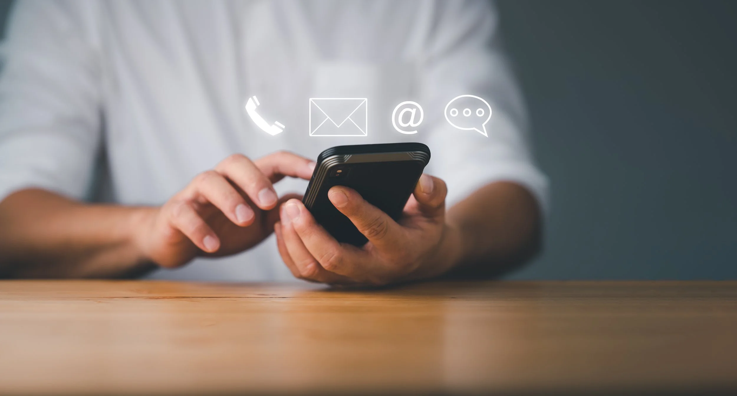 Person using a smartphone with icons for phone call, email, @ symbol, and chat message floating above.
