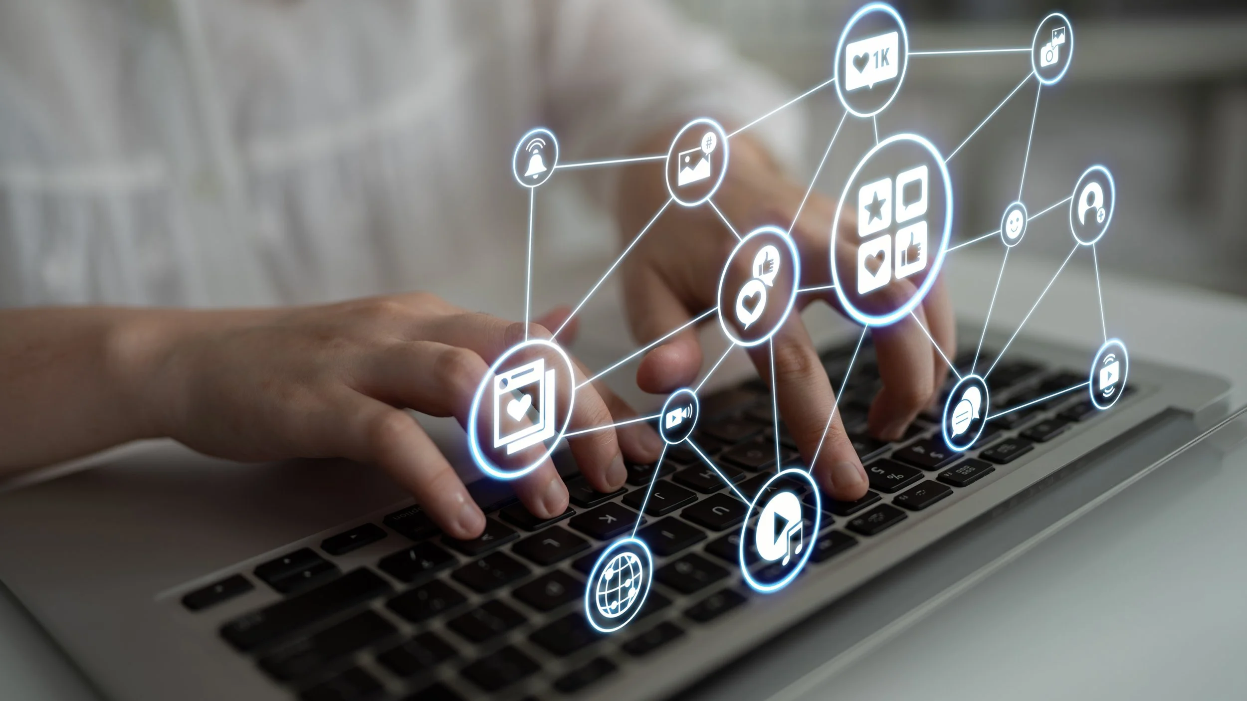 Hands typing on a laptop keyboard with digital social media icons and notifications floating above the keys.