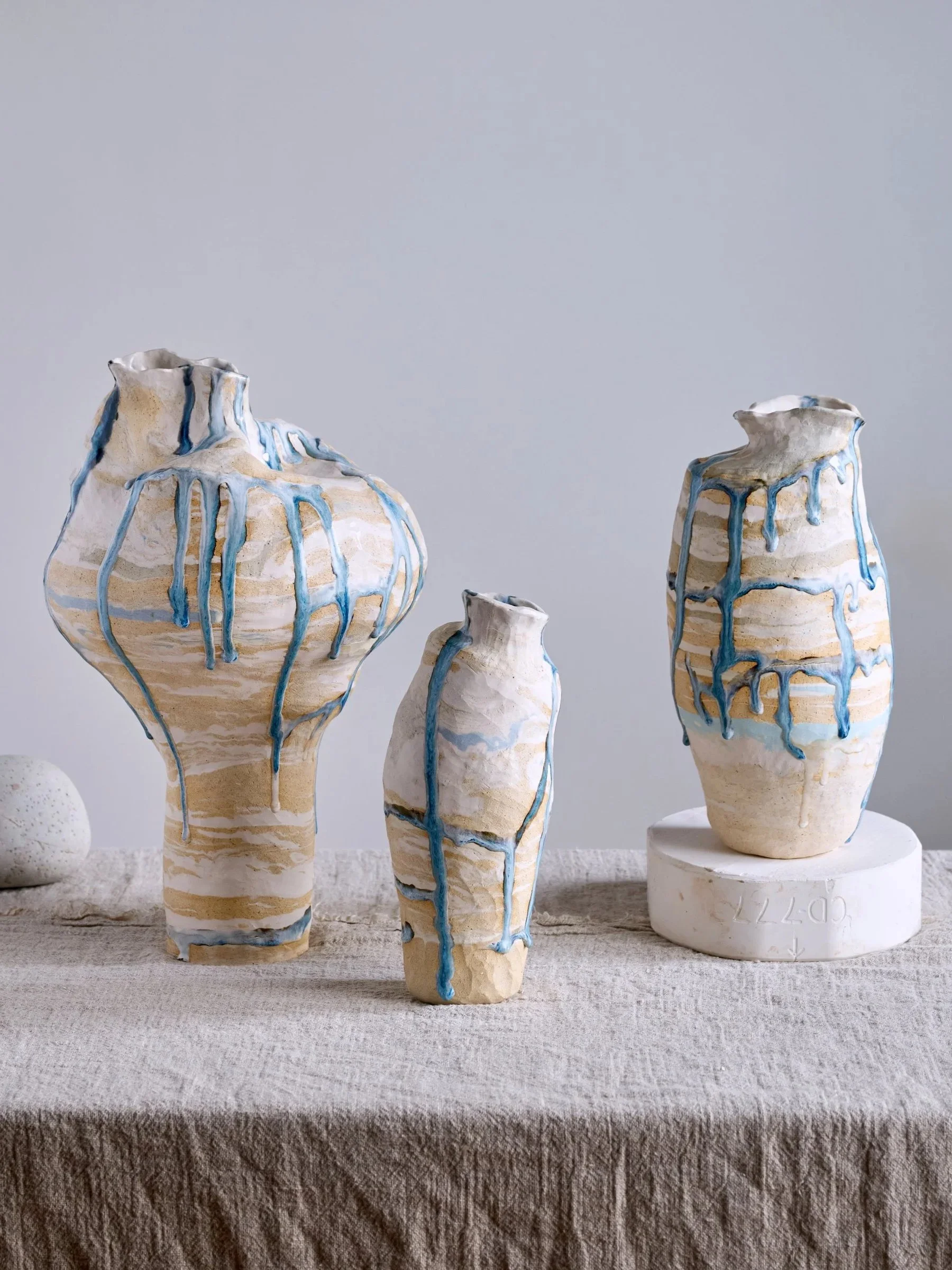Handcrafted ceramic vases with a white glaze and blue drips.