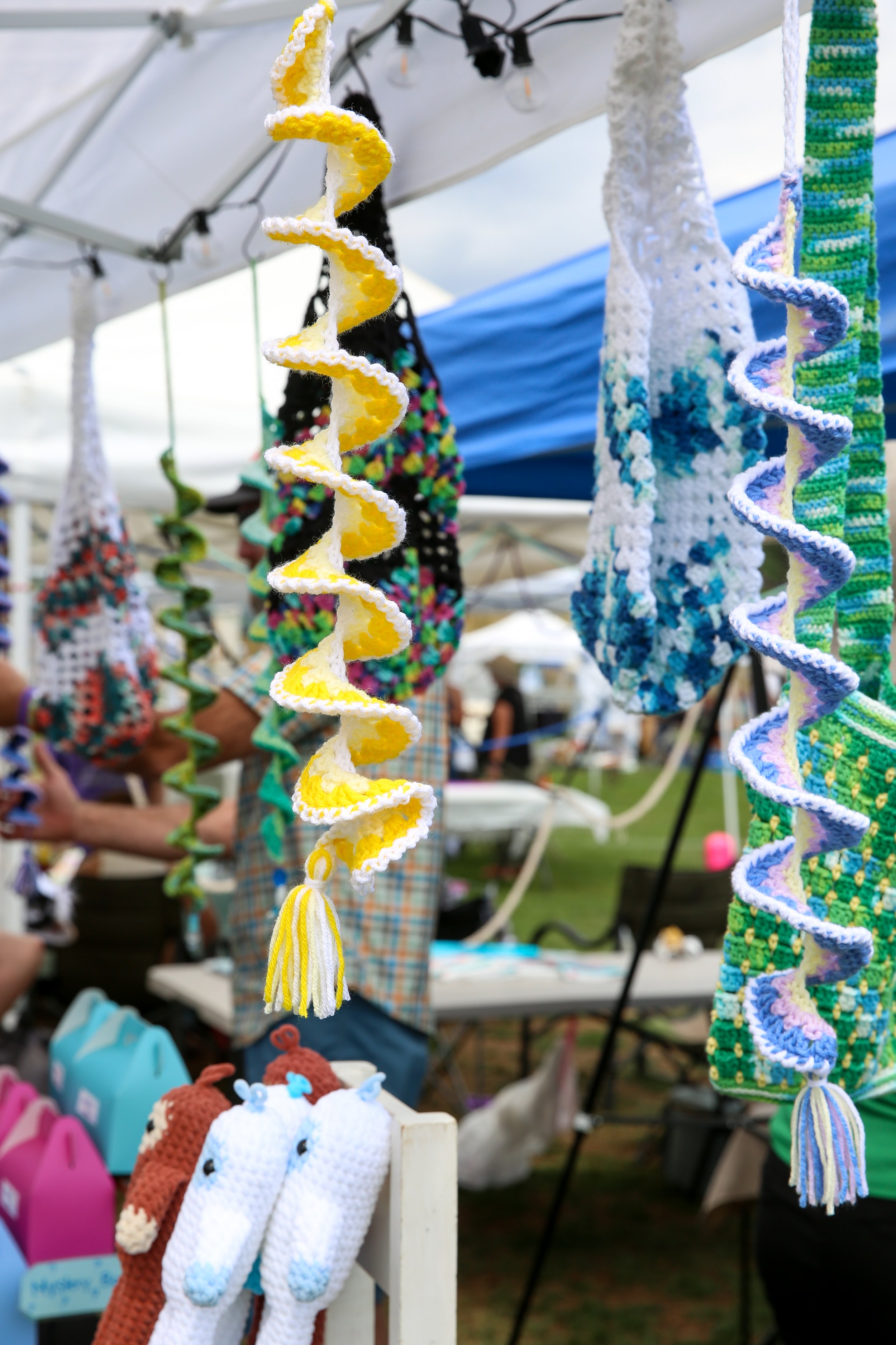 Colorful crocheted spirals hanging at a craft fair.