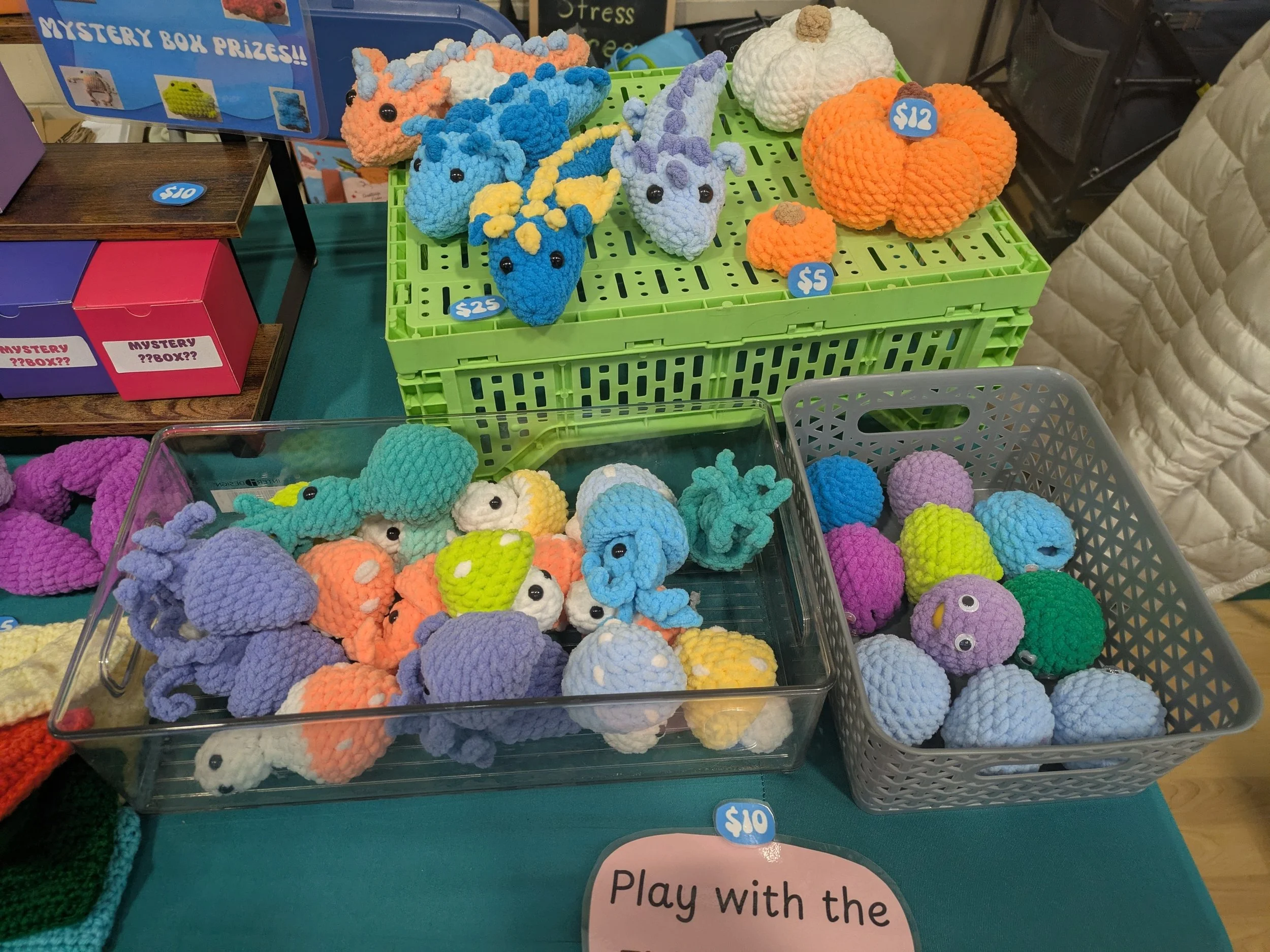 Colorful crocheted octopus, crab, and pumpkin toys for sale at a market booth, with prices labeled.