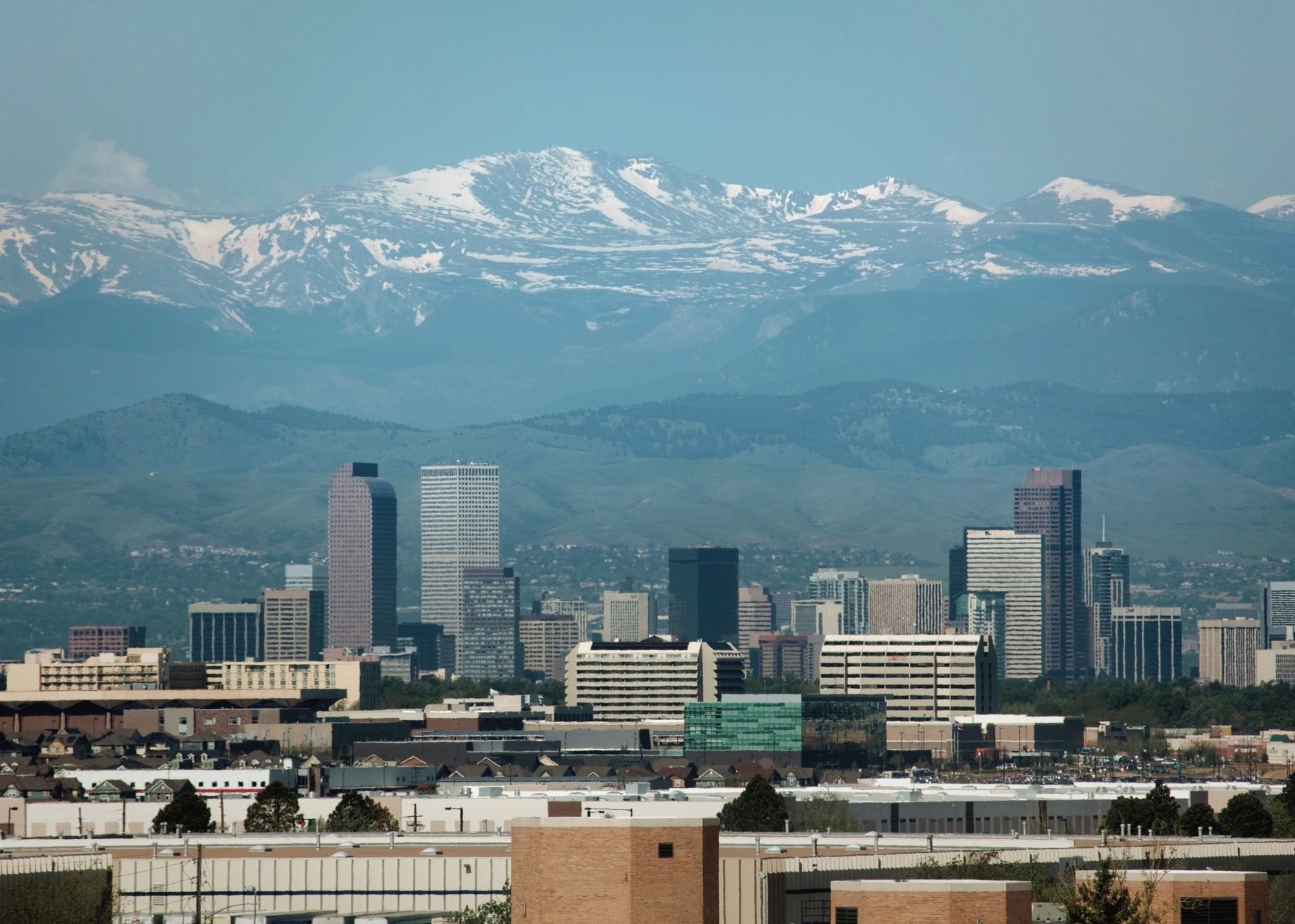 City skyline with high-rise buildings and mountains in the background, covered with snow.