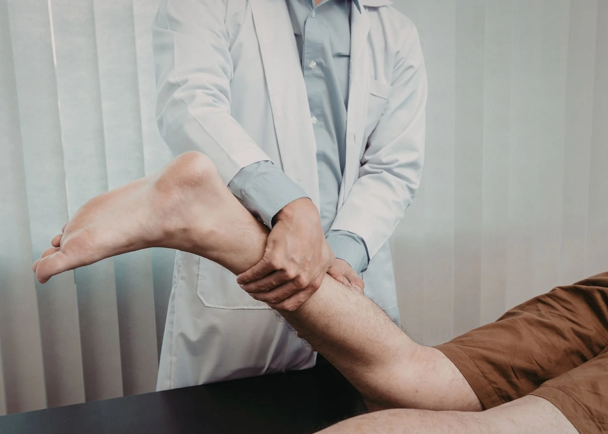 Doctor examining patient's leg in medical office.