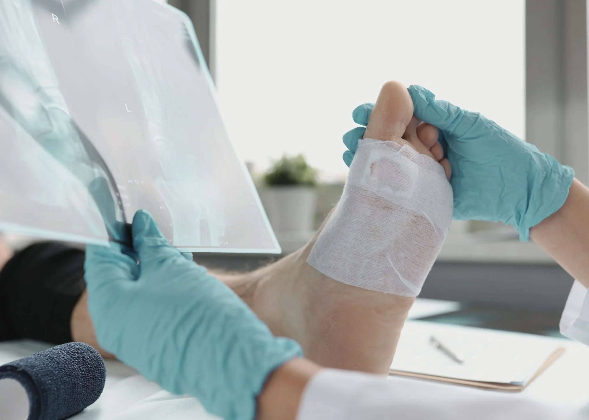 A healthcare professional holding a patient's hand, which is wrapped with a bandage, in a clinical setting.