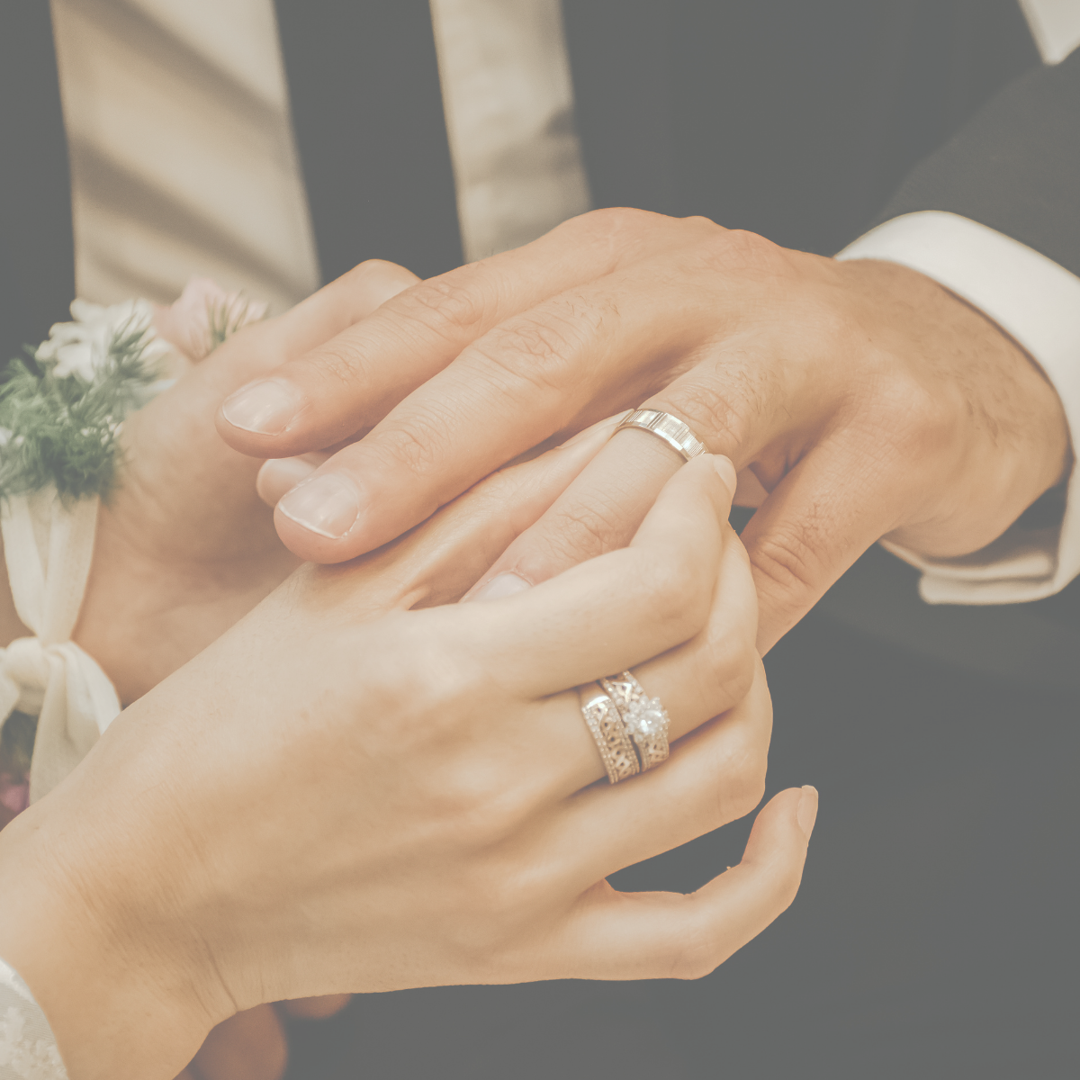Close-up of a couple exchanging rings during a wedding ceremony, with hands clasped and wedding bands visible.