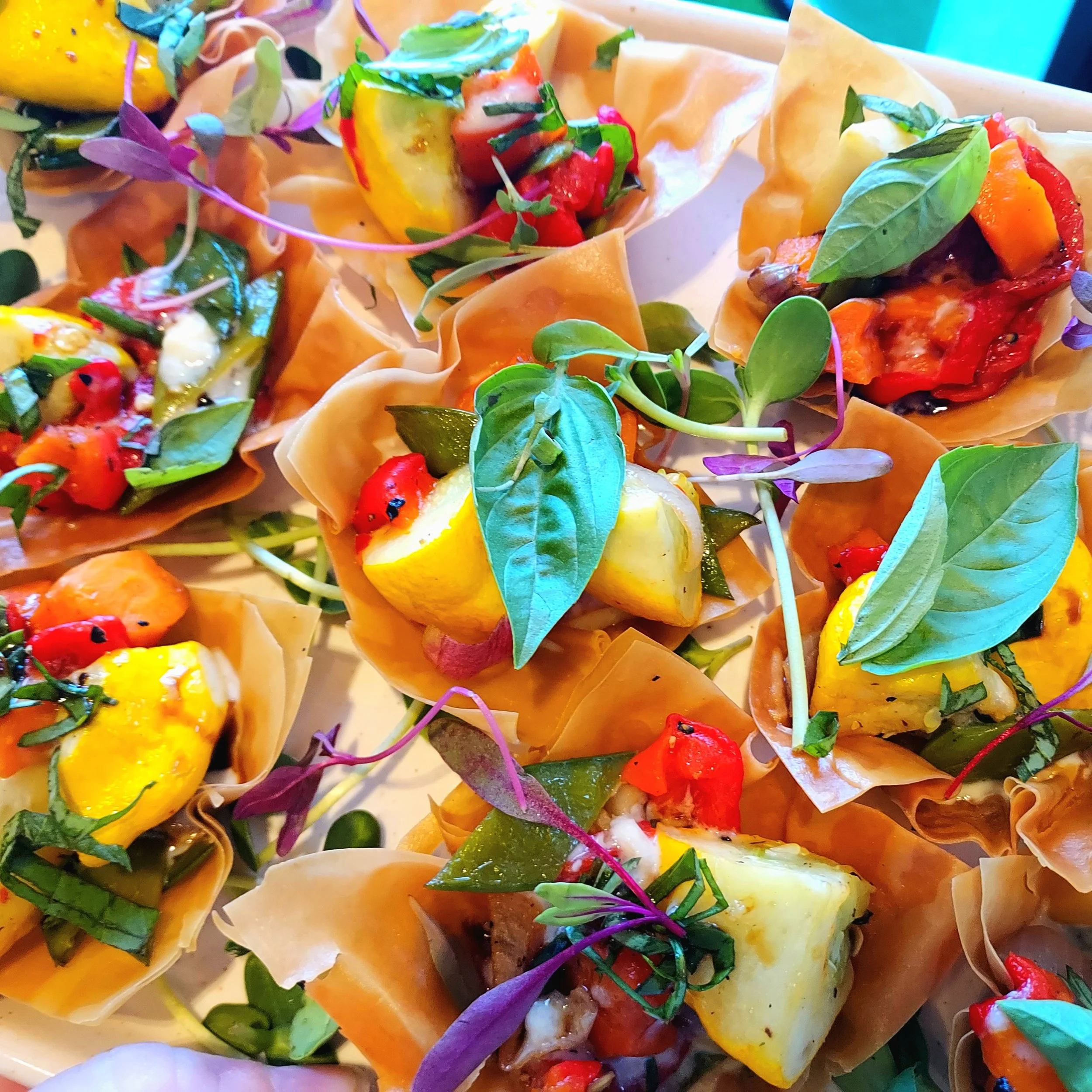 Close-up of colorful appetizers with vegetables, herbs, and possibly cheese, wrapped in pastry.