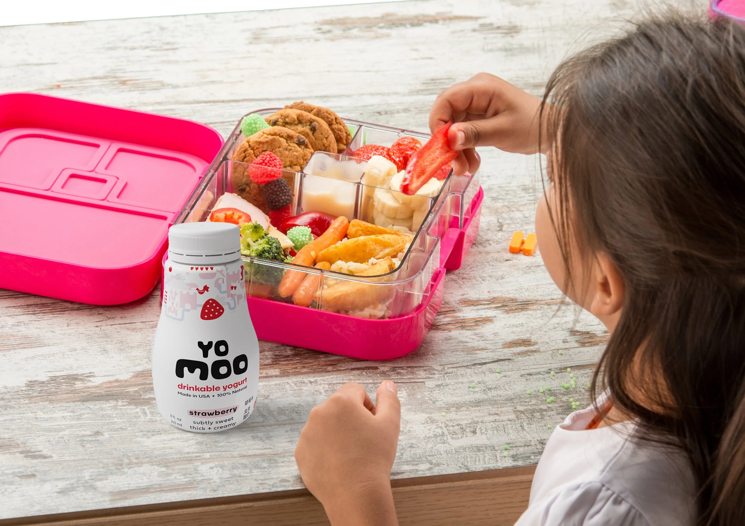 yomoo drinkable yogurt packaging mockup young girl eating box lunch with strawberry drinkable yogurt.
