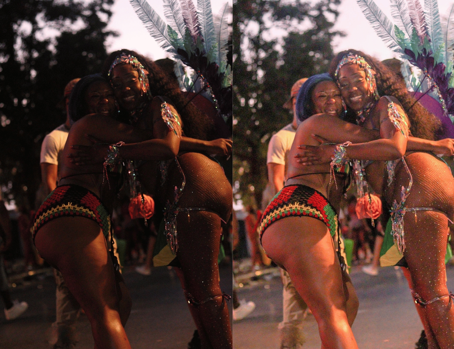 Two women in colorful carnival costumes hugging and smiling at an outdoor event during sunset, with a crowd of people in the background.