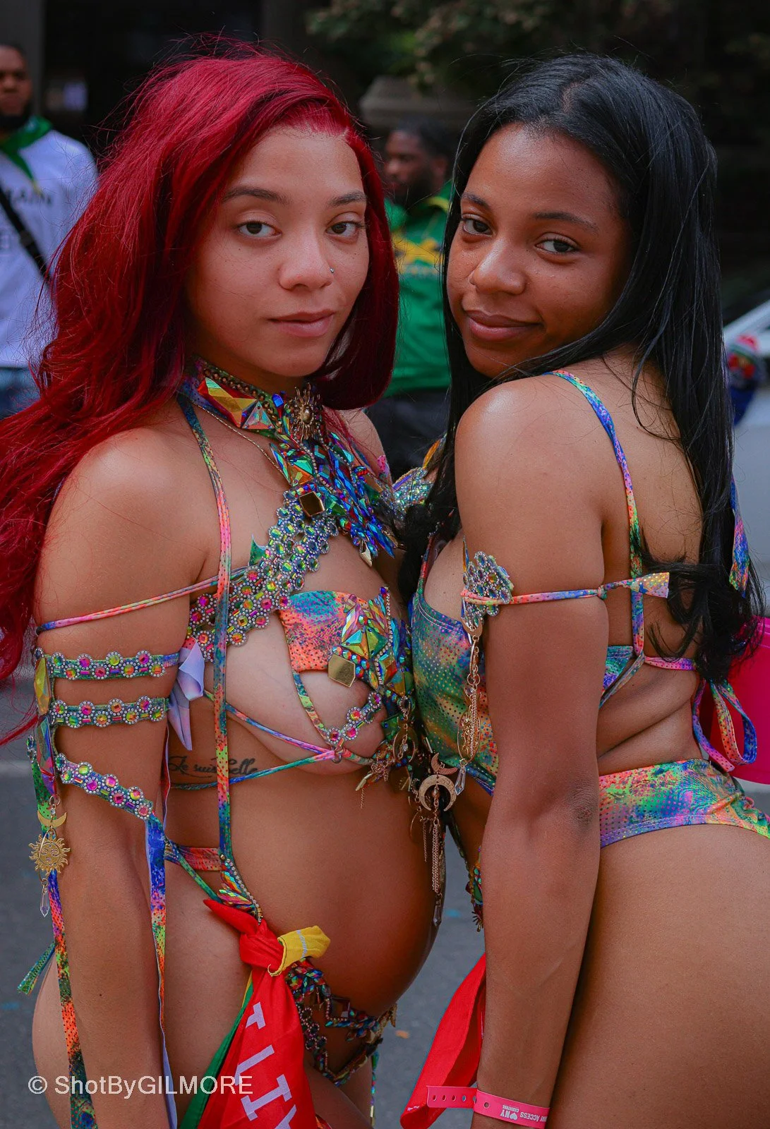 Two women dressed in colorful, extravagant costumes with beads and accessories, attending a carnival or festival.