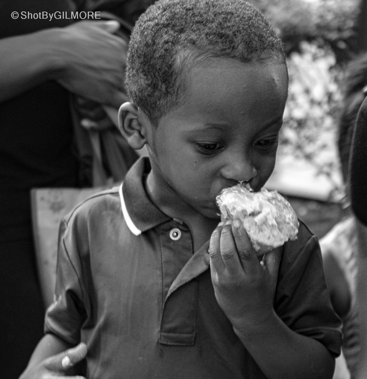 A young boy eating a piece of cake or bread, with a focused expression, in black and white.