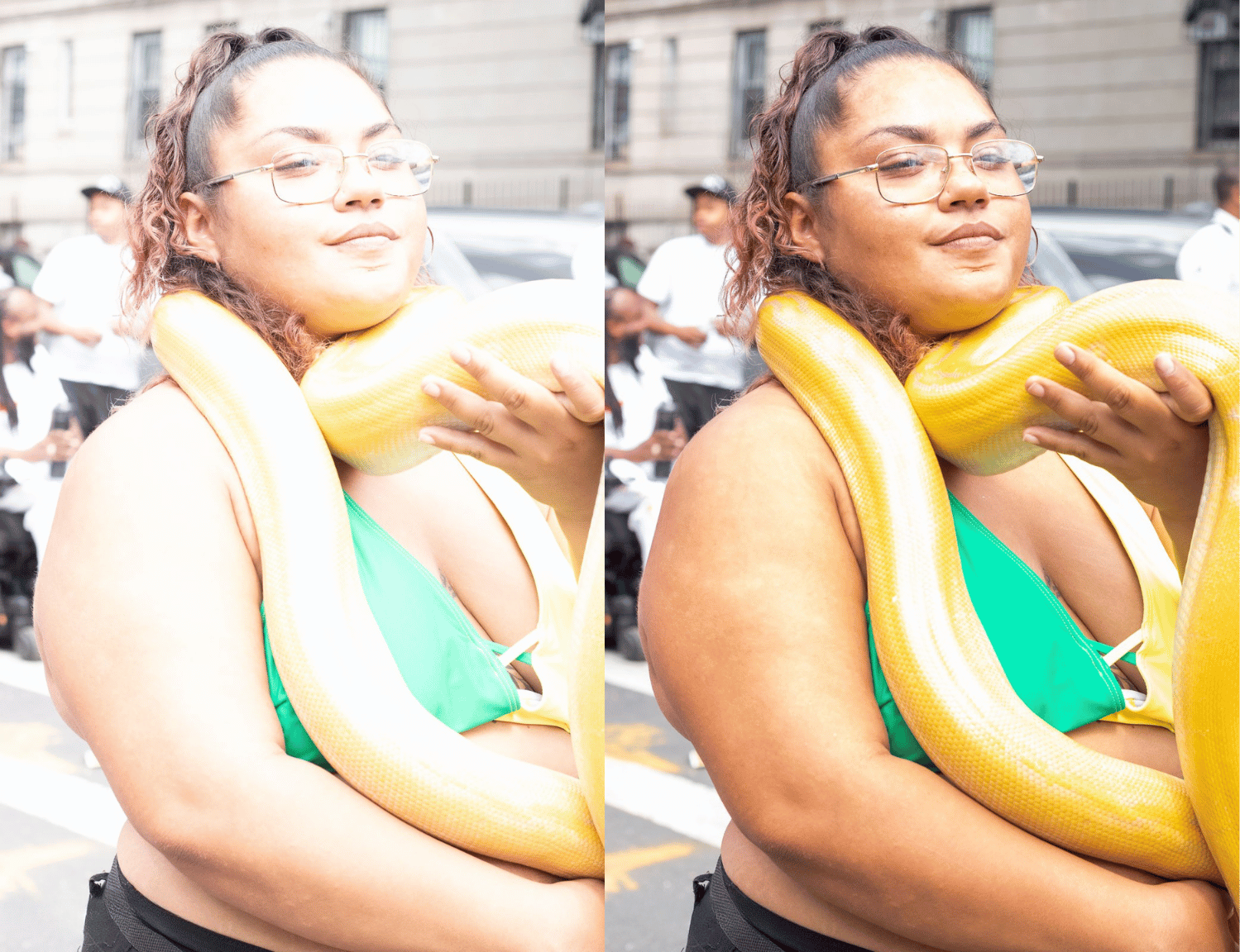 A woman with glasses and curly hair, wearing a green top, stands outdoors holding a yellow snake coiled around her shoulders and neck, with a city street background and several people in the background.