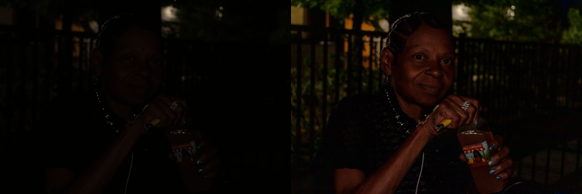 A woman holding a drink in an outdoor setting, smiling, with a fence and trees in the background.