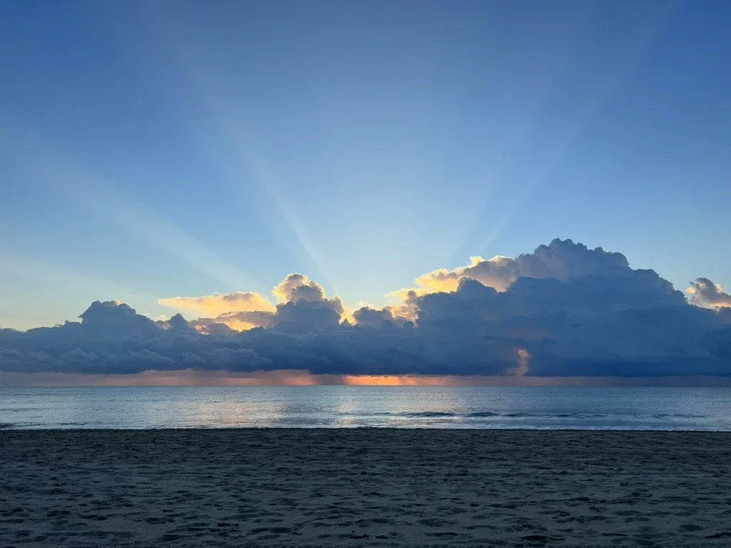 Sunset over the ocean with clouds and rays of sunlight