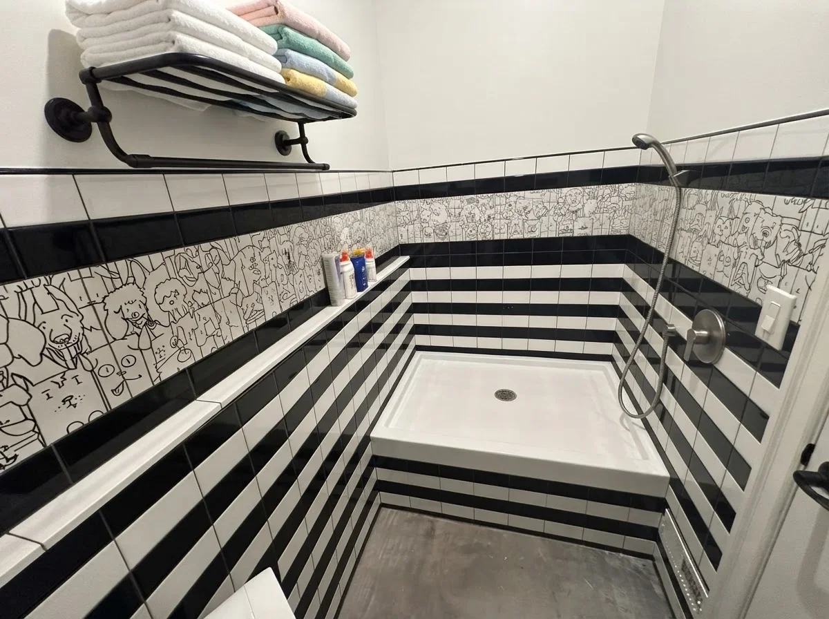 Custom mudroom dog washing station featuring a built-in elevated pet bath, striking horizontal tile work, and custom dog-themed accent panels.
