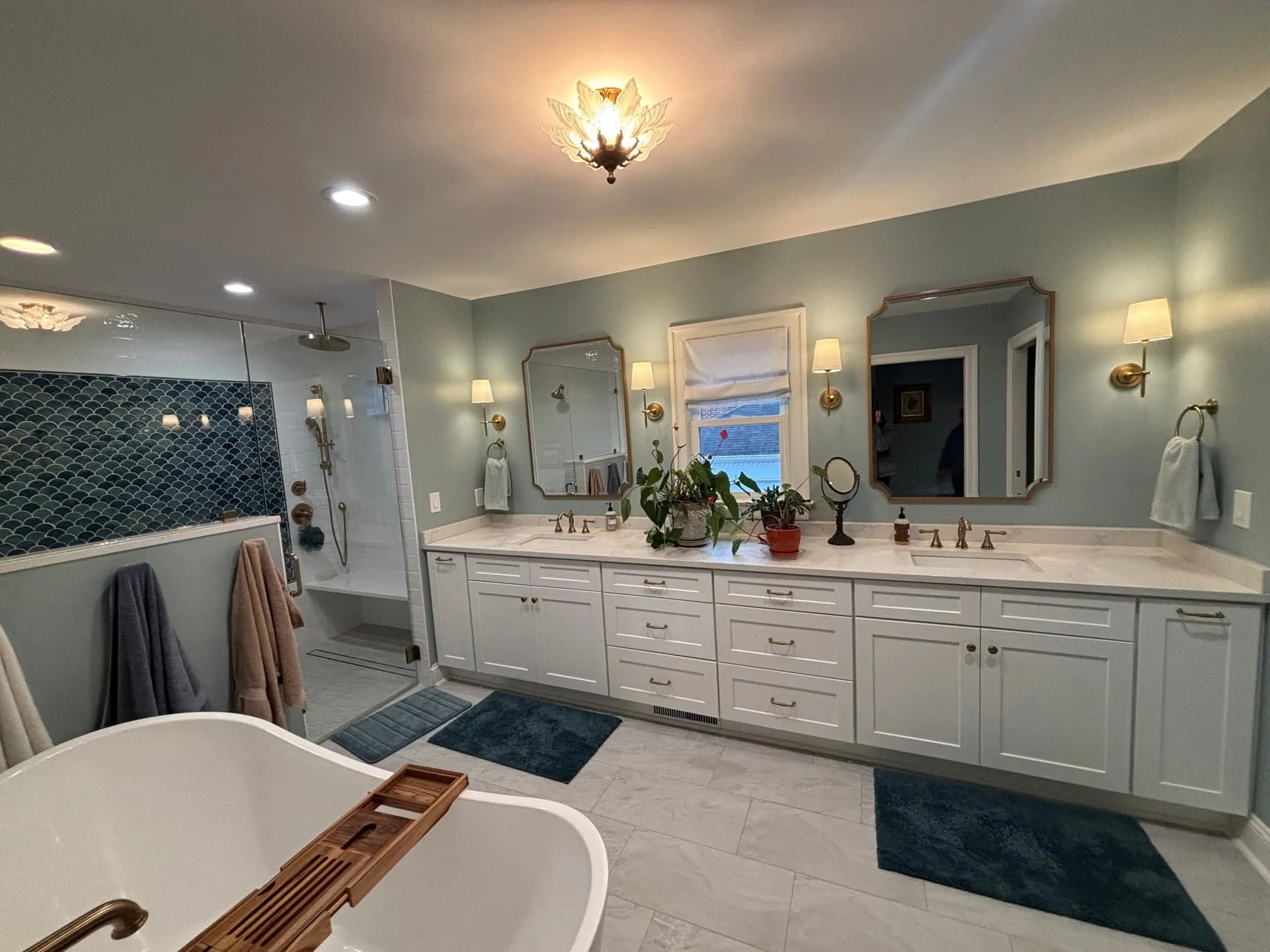 A bright, spa-inspired luxury bathroom remodel in Atlanta, GA, featuring a double white vanity, custom walk-in shower with a blue mosaic tile niche, and a freestanding soaking tub by Mahfoud Construction Inc.