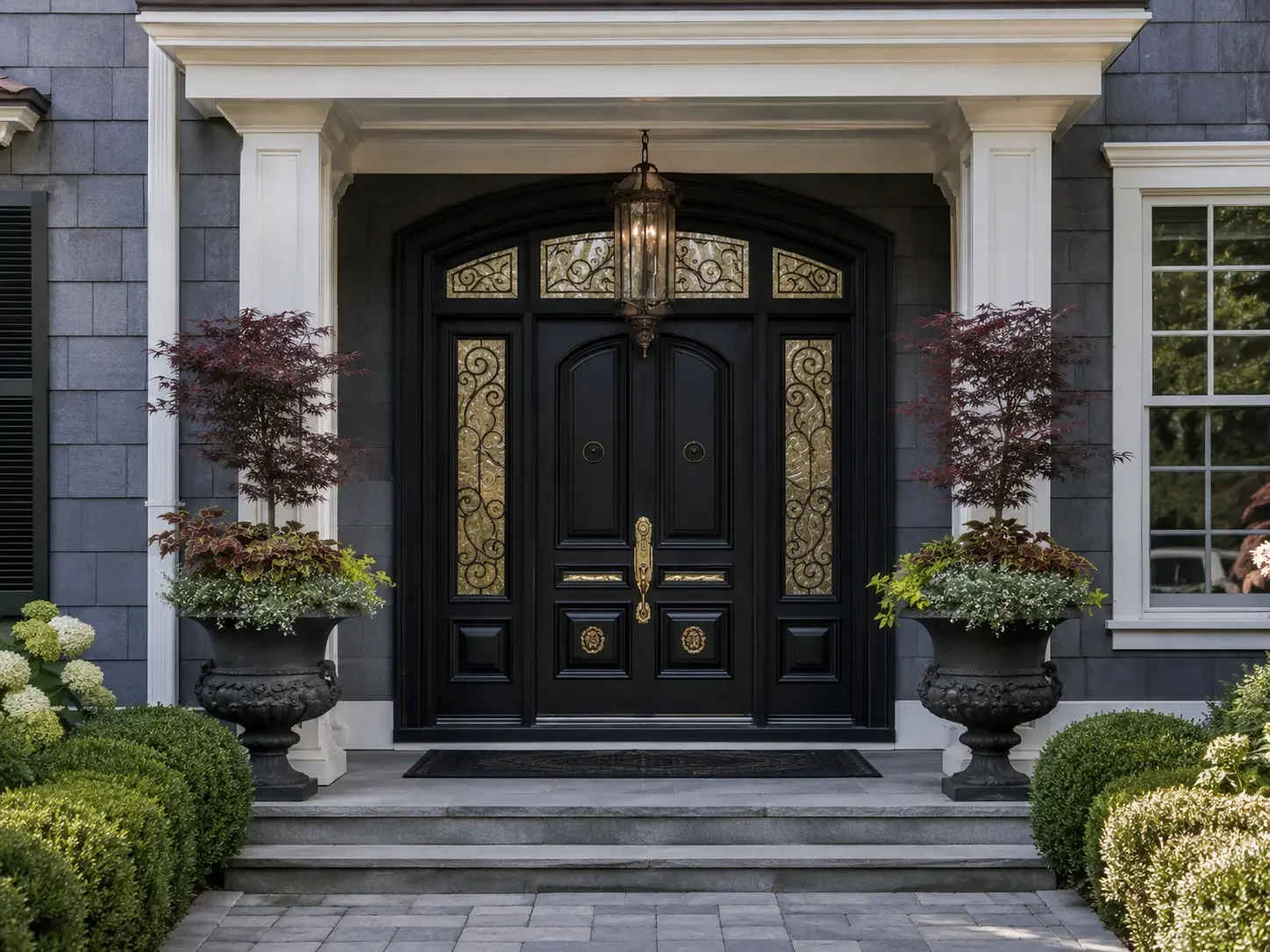 Luxury portico entranceway remodel in Tucker, Georgia showcasing a classic black double door, ornate glass side panels, overhead lantern lighting, and precision masonry.
