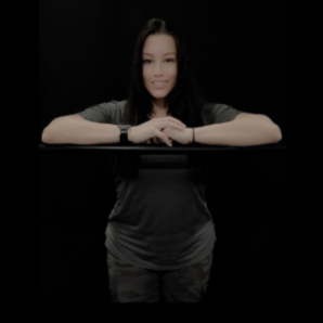 A woman sitting behind a black barrier, smiling with her arms resting on it.