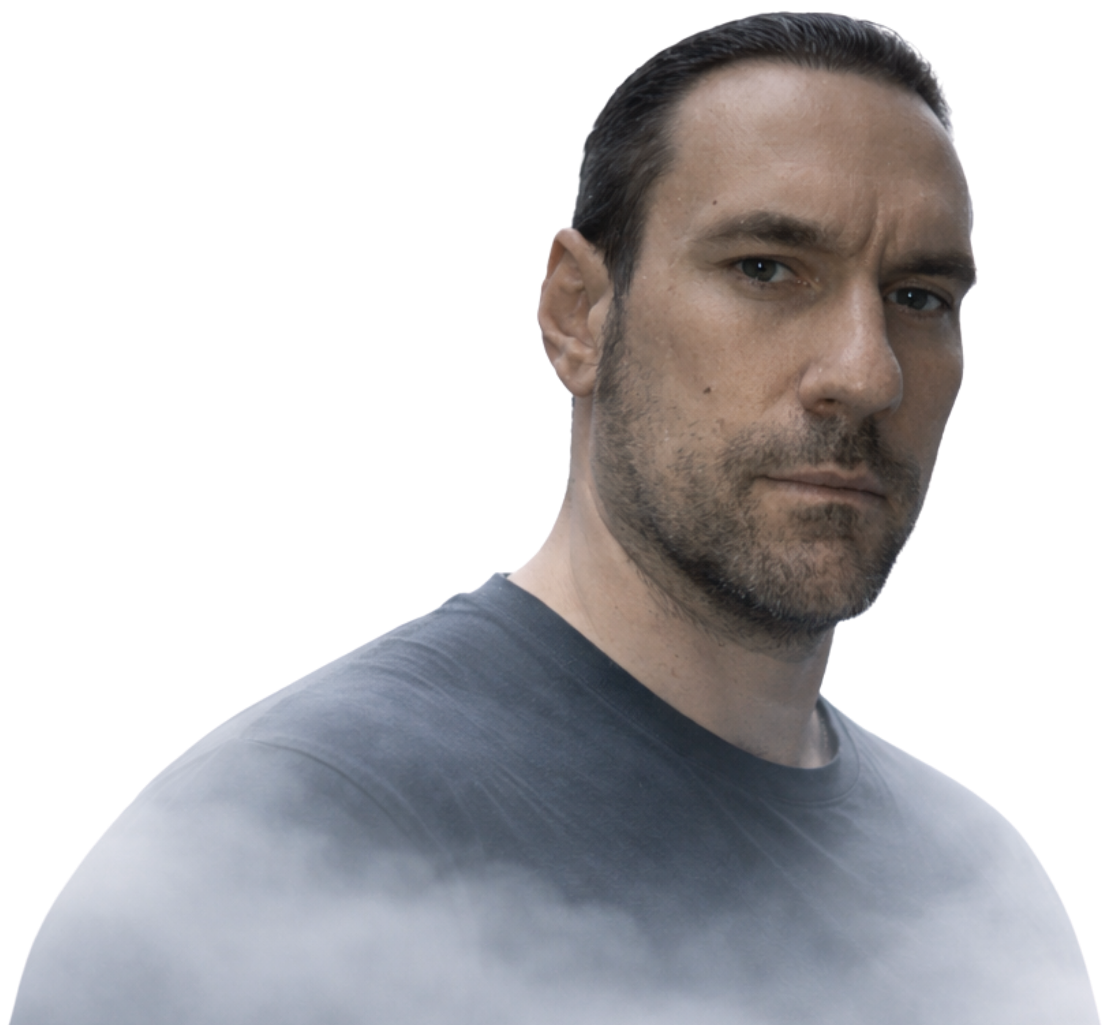 A close-up portrait of a man with dark hair, light skin, and blue eyes, wearing a dark gray T-shirt.