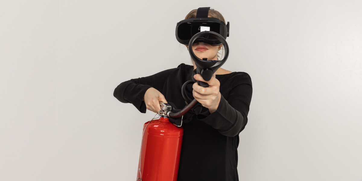 Person med svart klær og VR-briller holder en brannslukker mot kameraet.