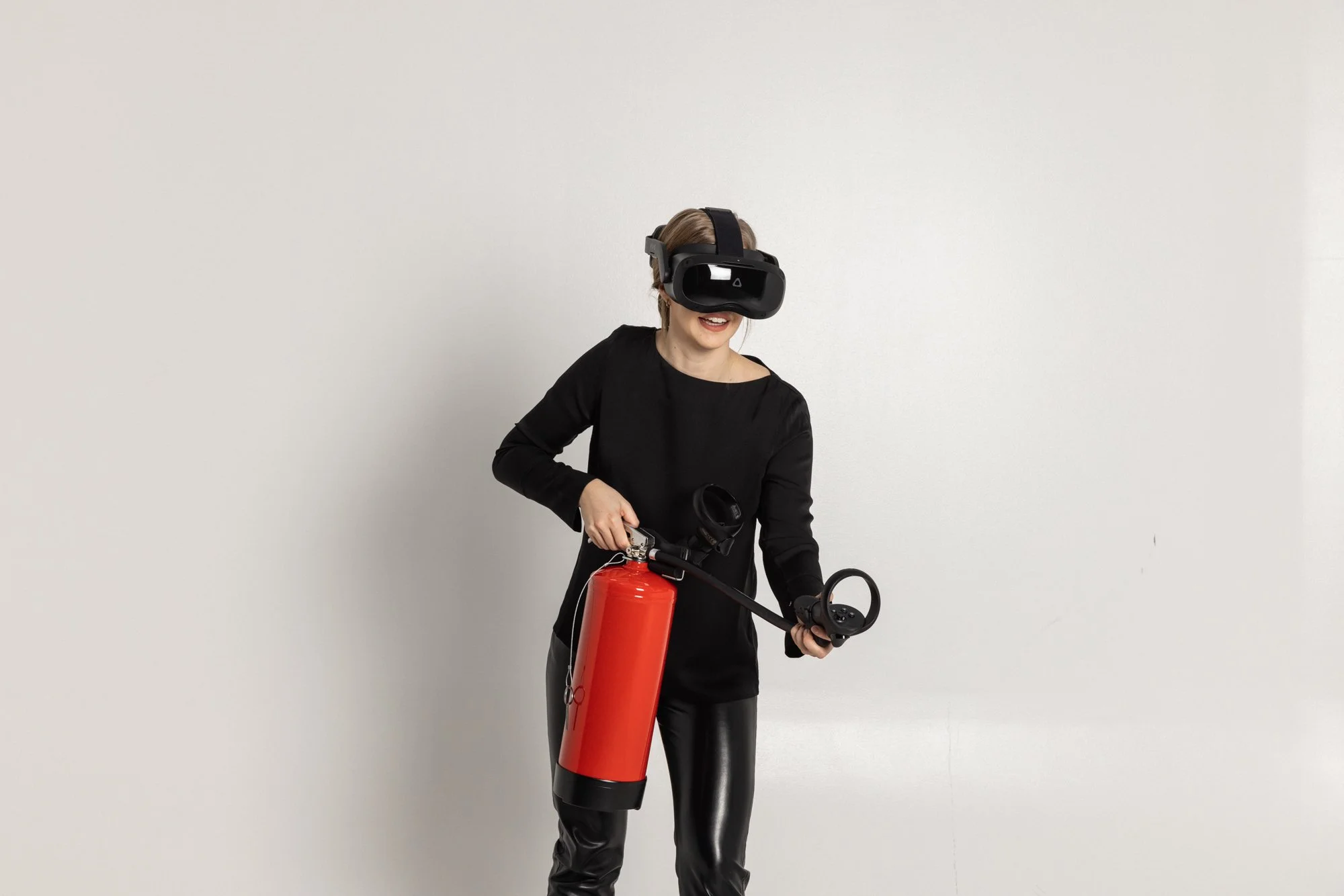 Kvinde bruker en VR-headset og holder en brannslukker
