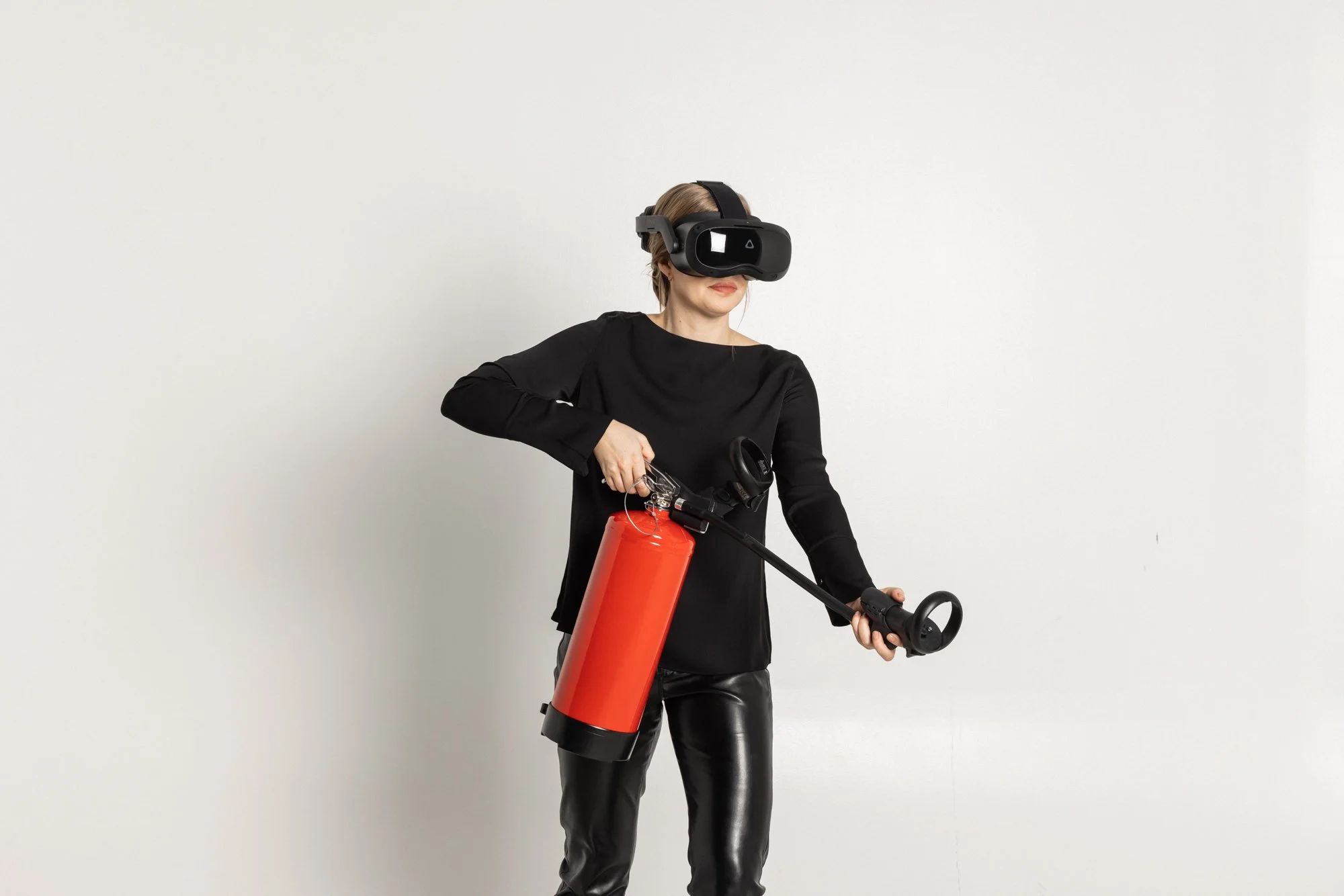 Kvinne iført VR-headset og holder en brannslukker på en tom vegg.