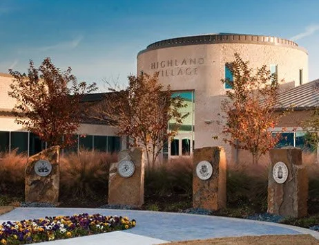 Highland Village municipal building with landscaped grounds and stone memorial markers